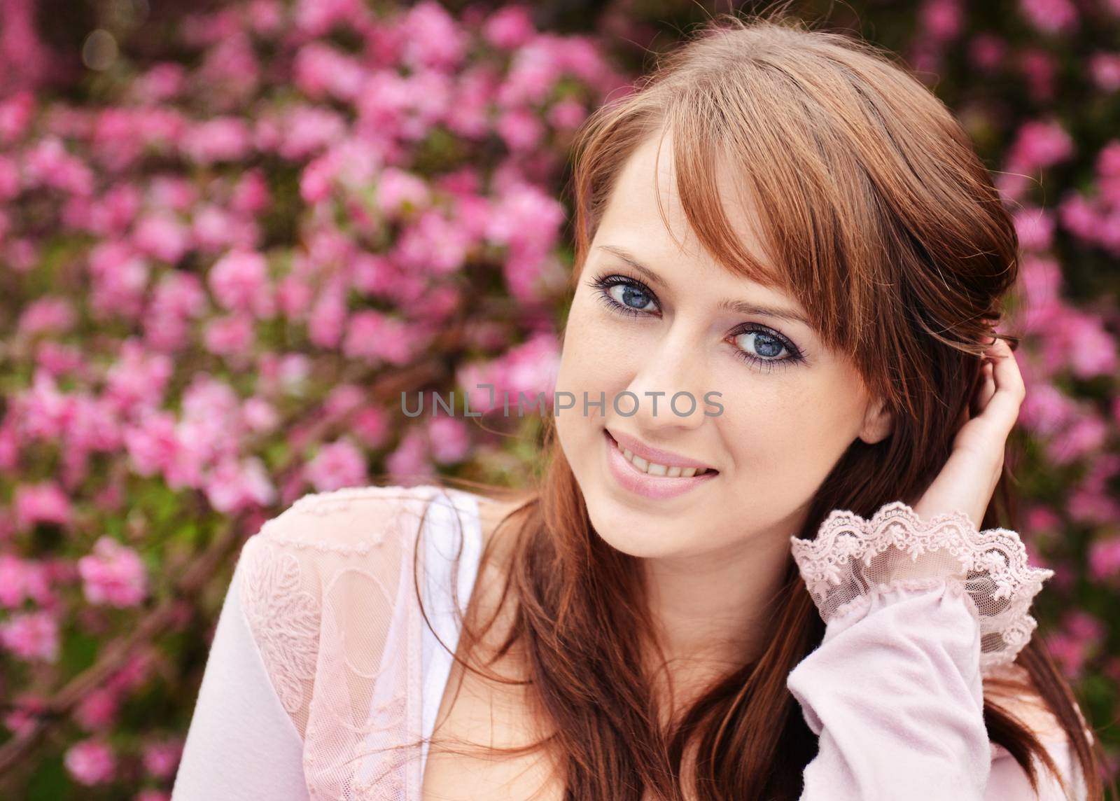 Beautiful girl posing over spring flowers background