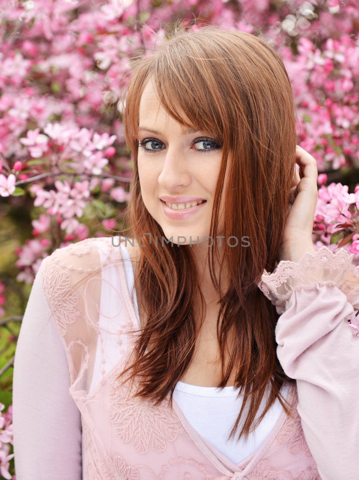 Beautiful girl posing over spring flowers background