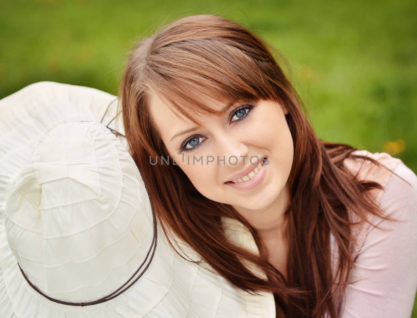 beautiful girl with sun hat over green grass background