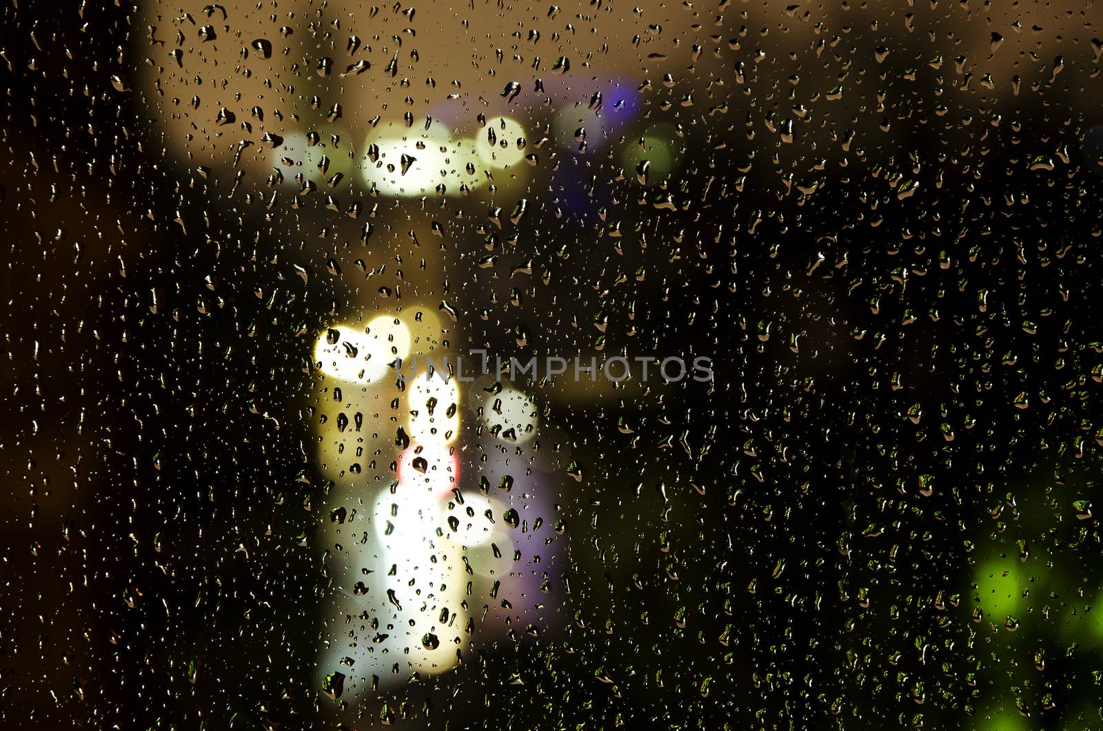 view of the city lights through rainy window