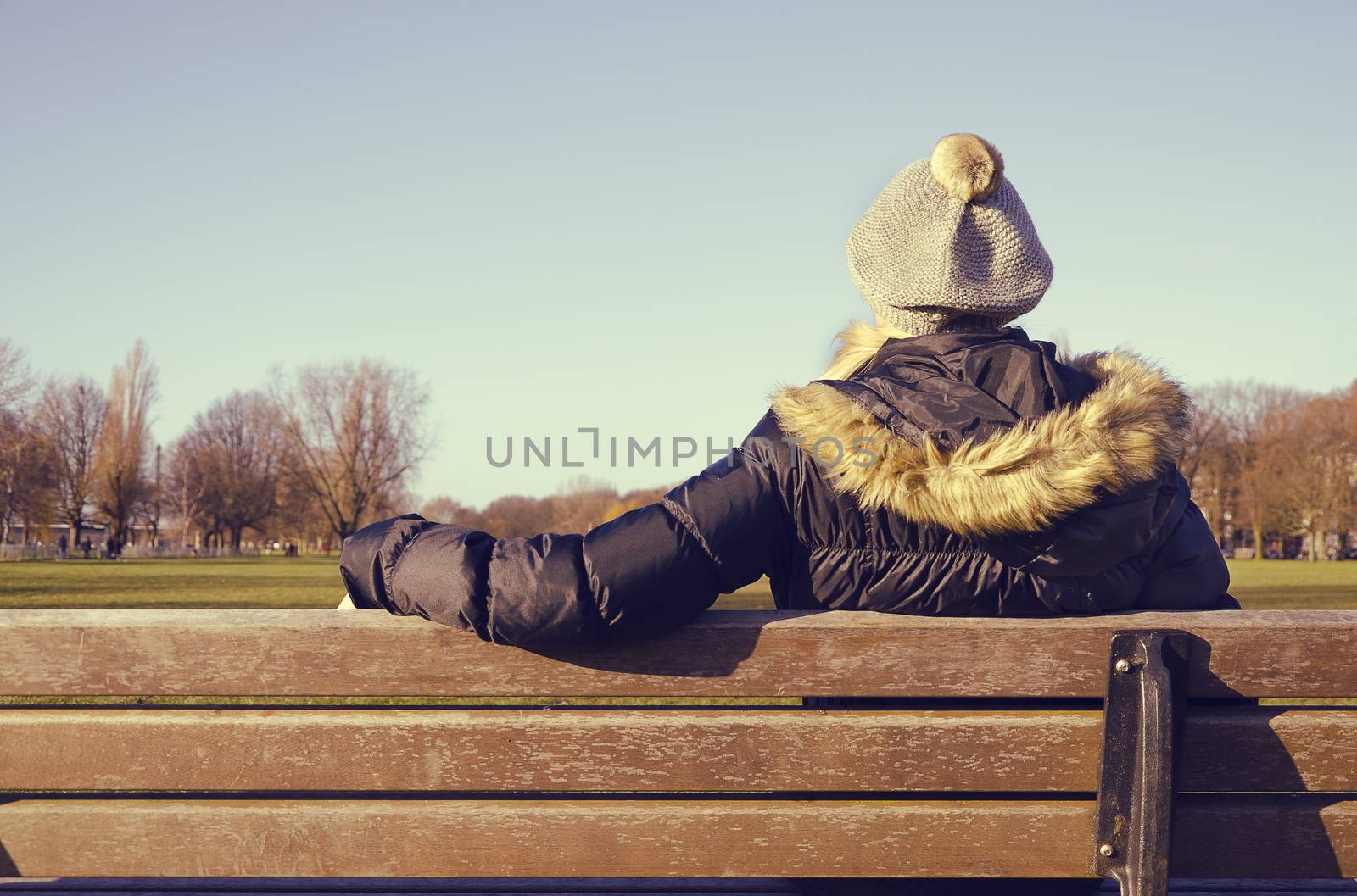 woman resting on a park bench looking at the distance deep in thought