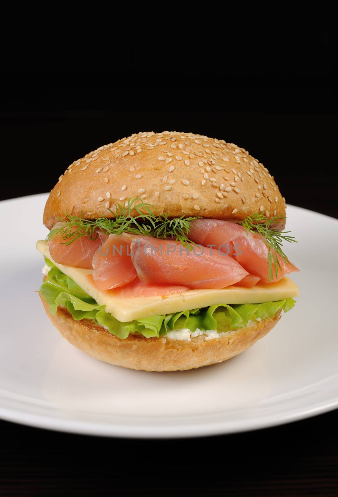 Appetizing bun with sesame seeds and thin slices of cheese with salmon