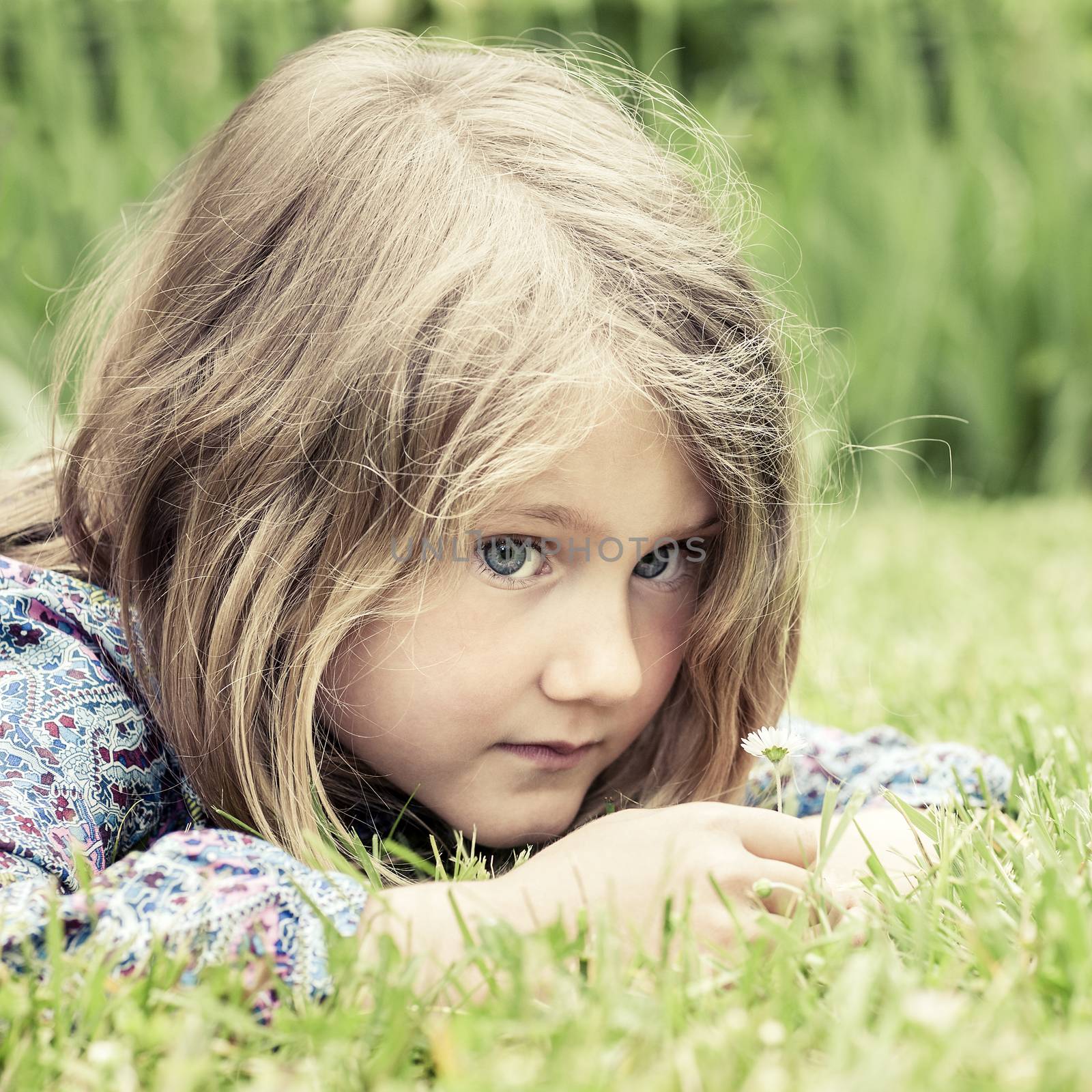 Pensive girl lying on grass 