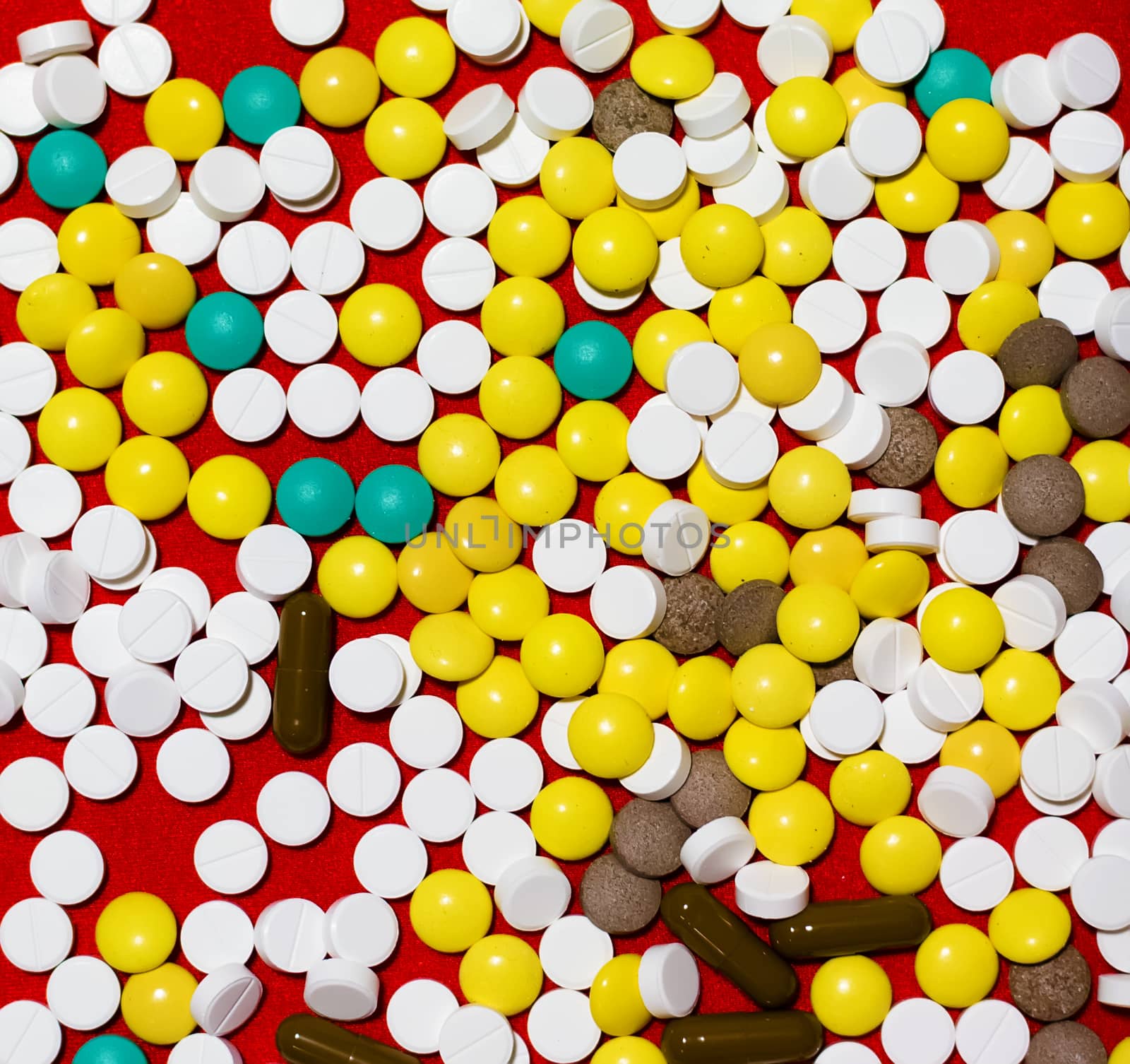 large pile of different pills on a red fabric background