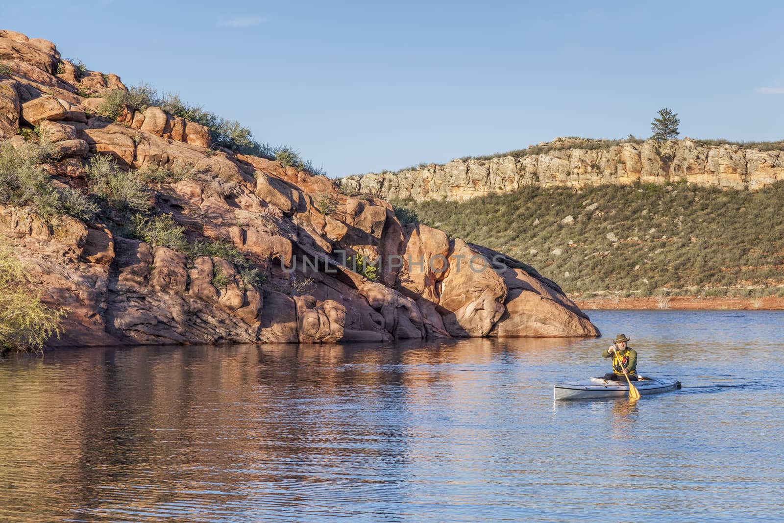 senior male paddling a decked expedition canoe on Horsetooth Reservoir near Fort Collins, Colorado