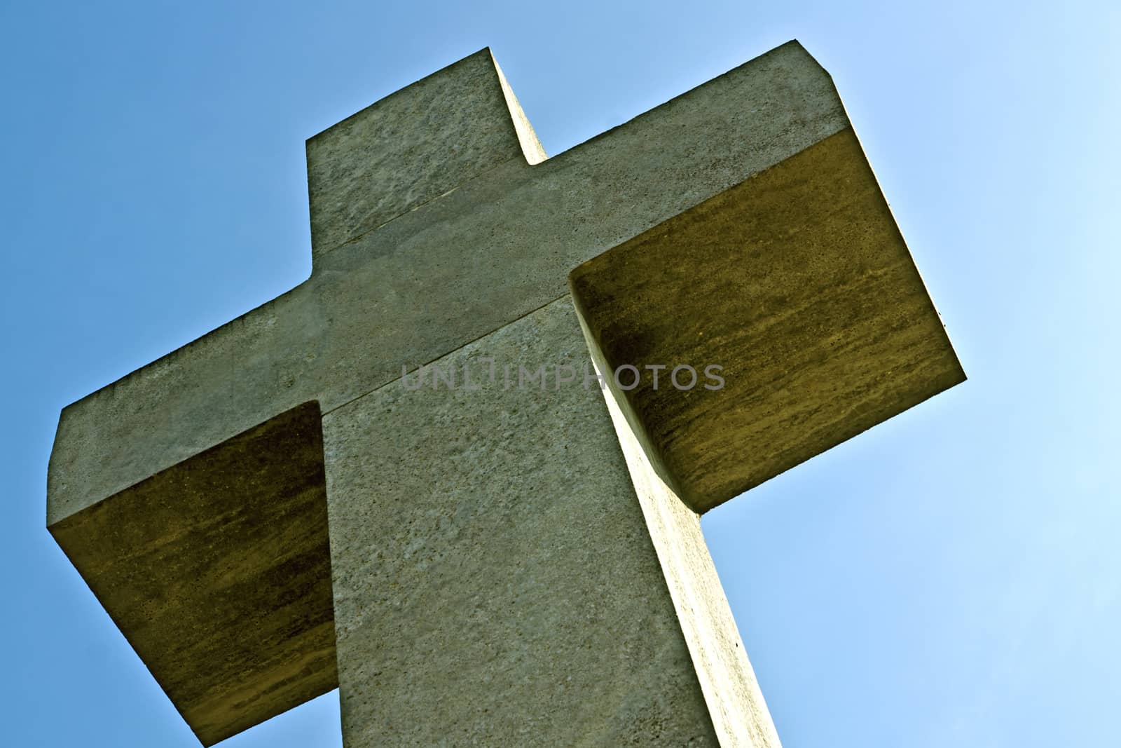 A large stone cross photographed in a cemetery with graves of war.