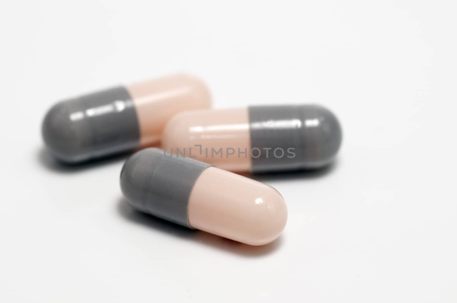 Three capsules or pills on white background