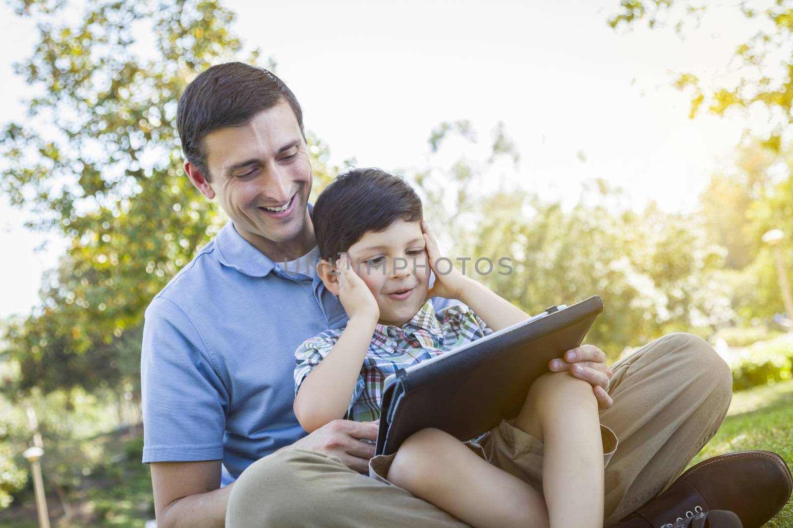 Handsome Mixed Race Father and Son Playing on a Computer Tablet Outside.