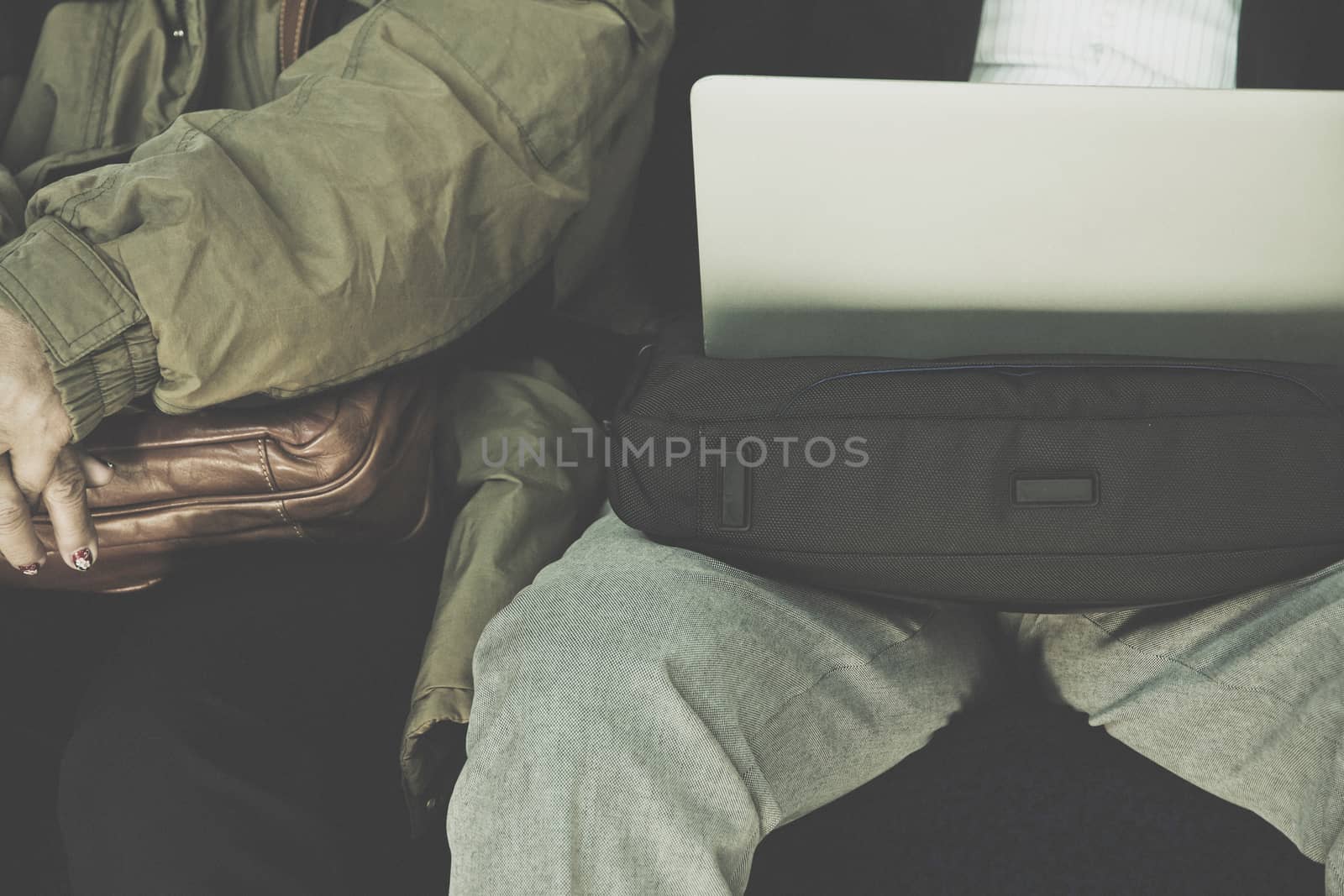 Businessman sitting on seat of train and playing Laptop
