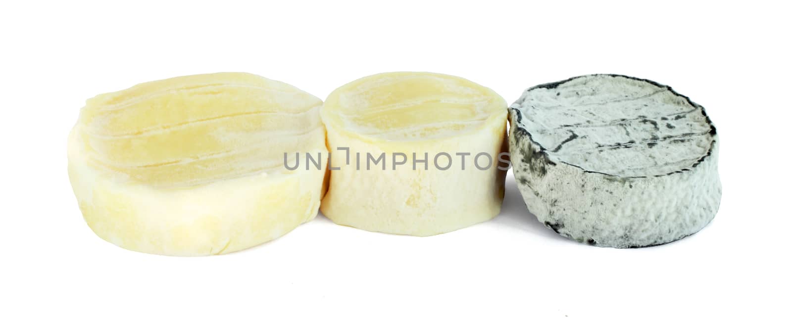 Three portions of soft round goat cheese isolated on white background