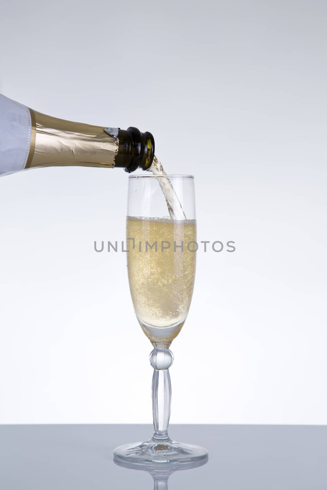 Champagne pouring into a glass, natural reflection, studio shot on grey background 