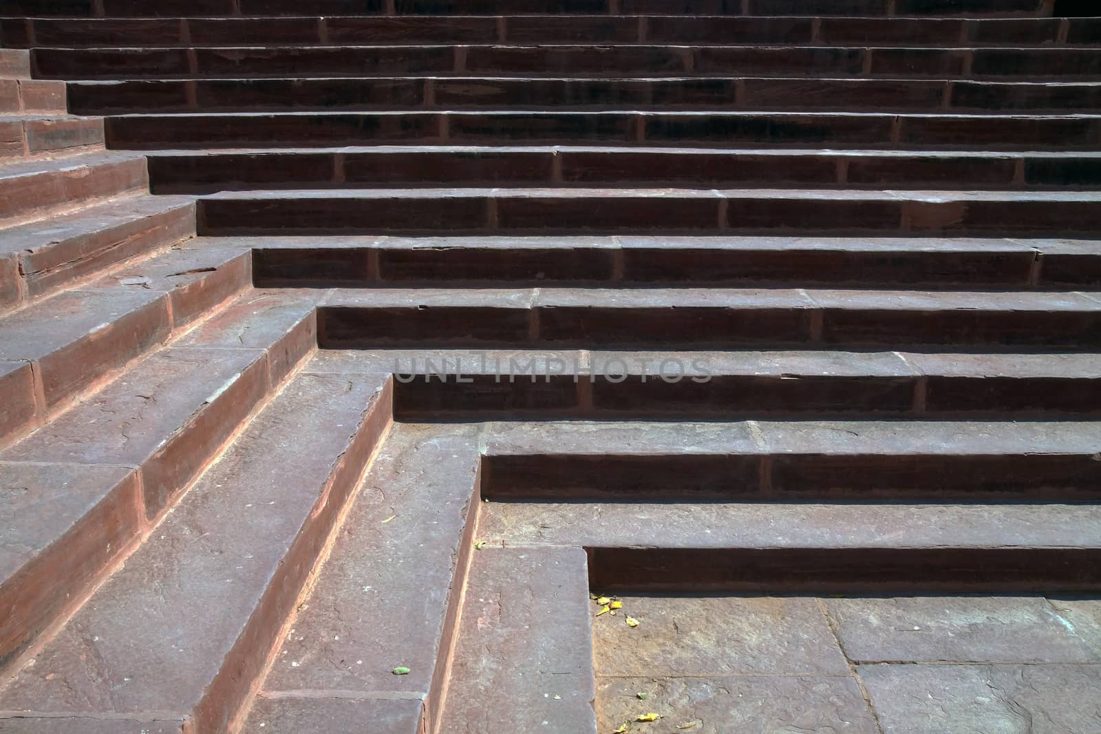 morning sunlight on red sandstone stairs creates light and shadow design in lines