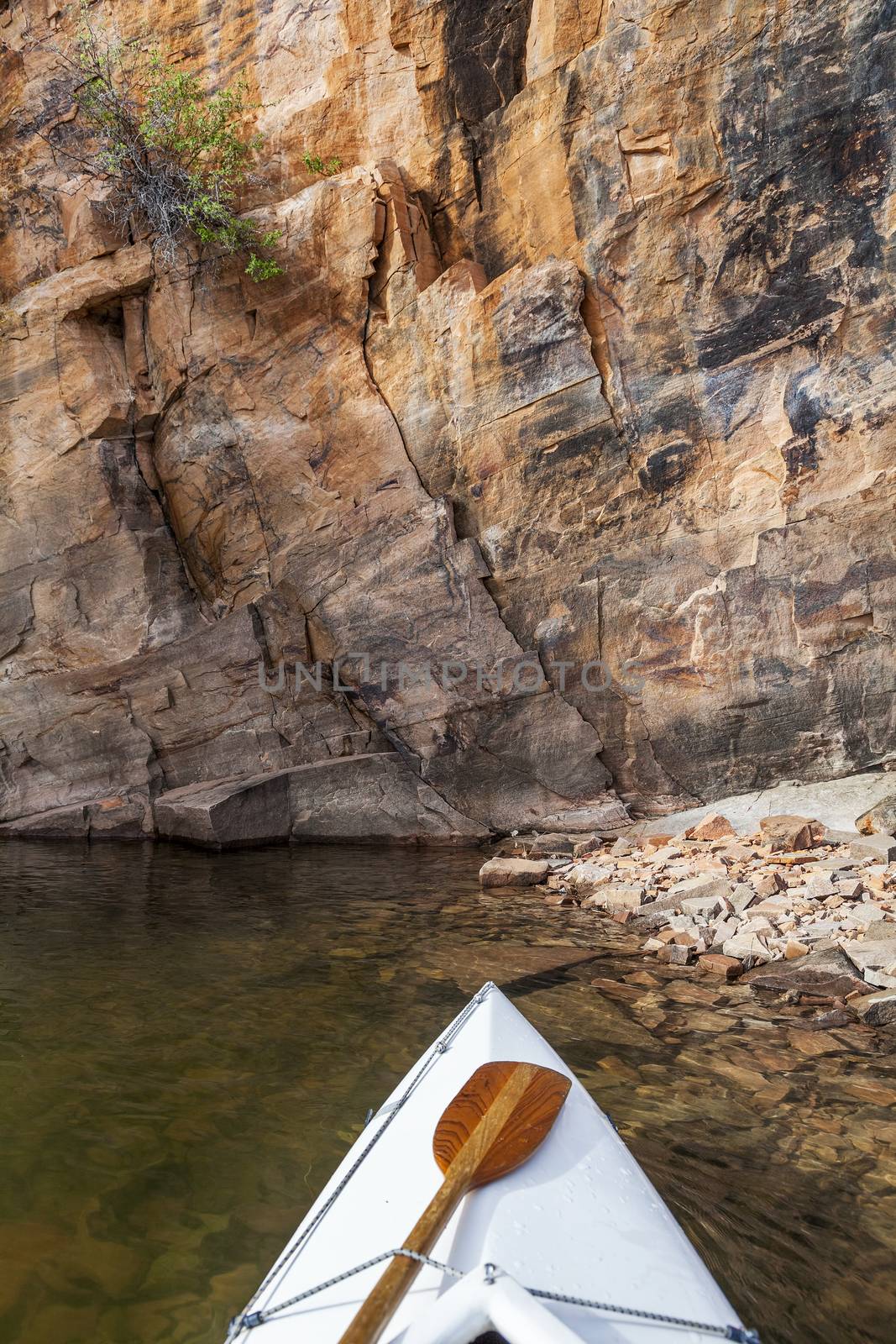 canoe bow with a paddle on Horsetooth Reservoir with a high sandstone cliff, Fort Collins, Colorado