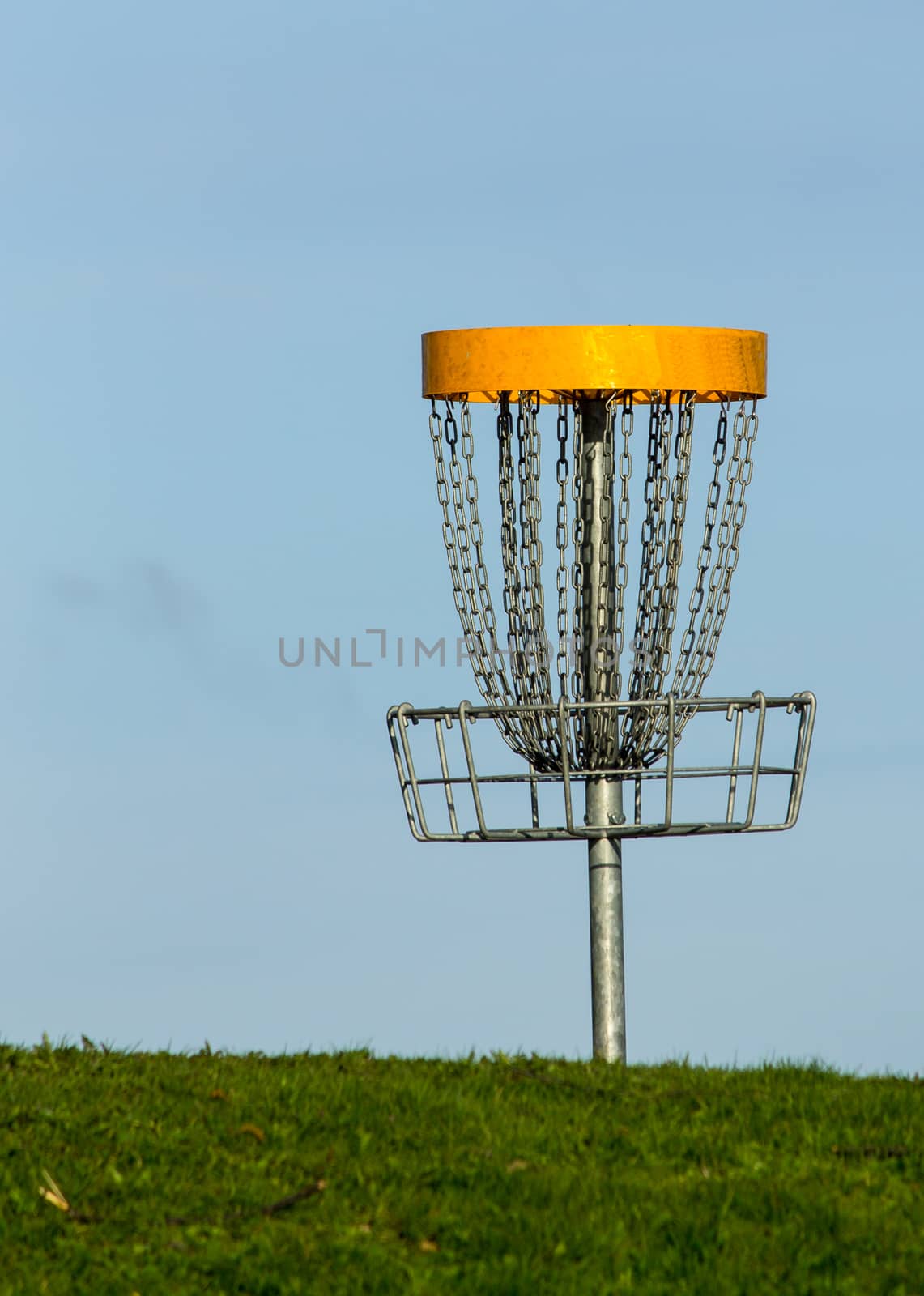 Frisbee golf basket against blue sky on the green grass