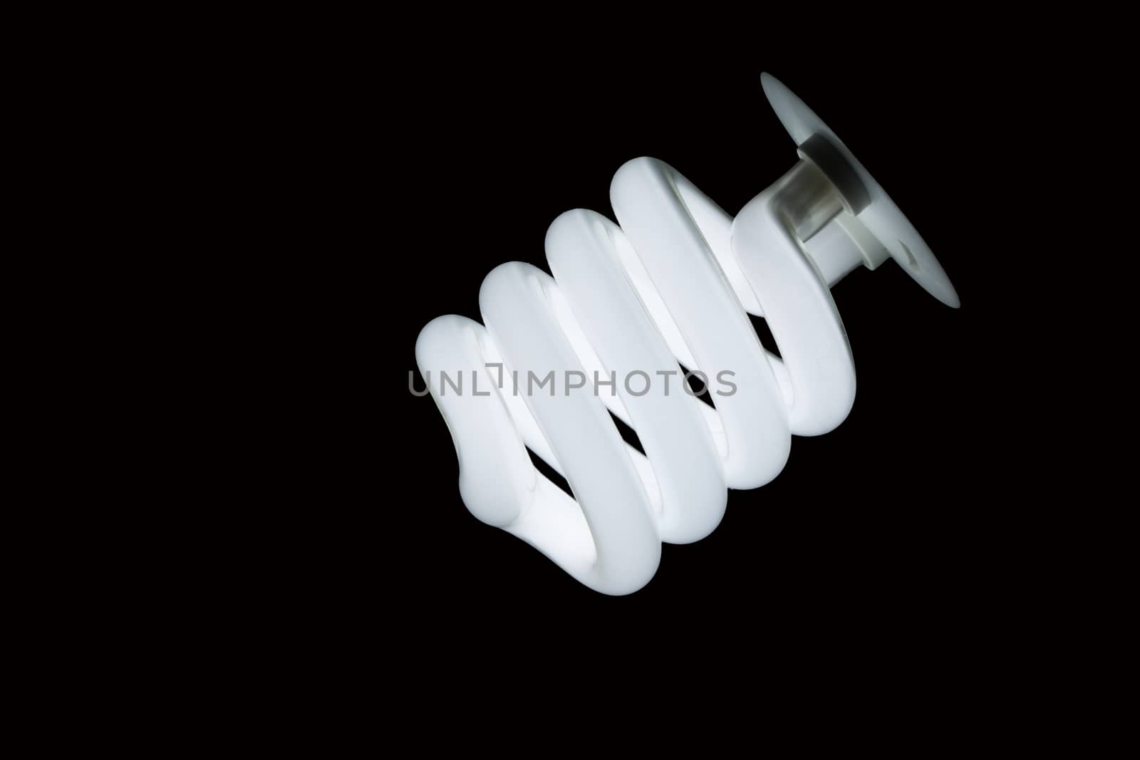 Glowing Spiral CFL Lamp isolated against Black background in diagonal composition