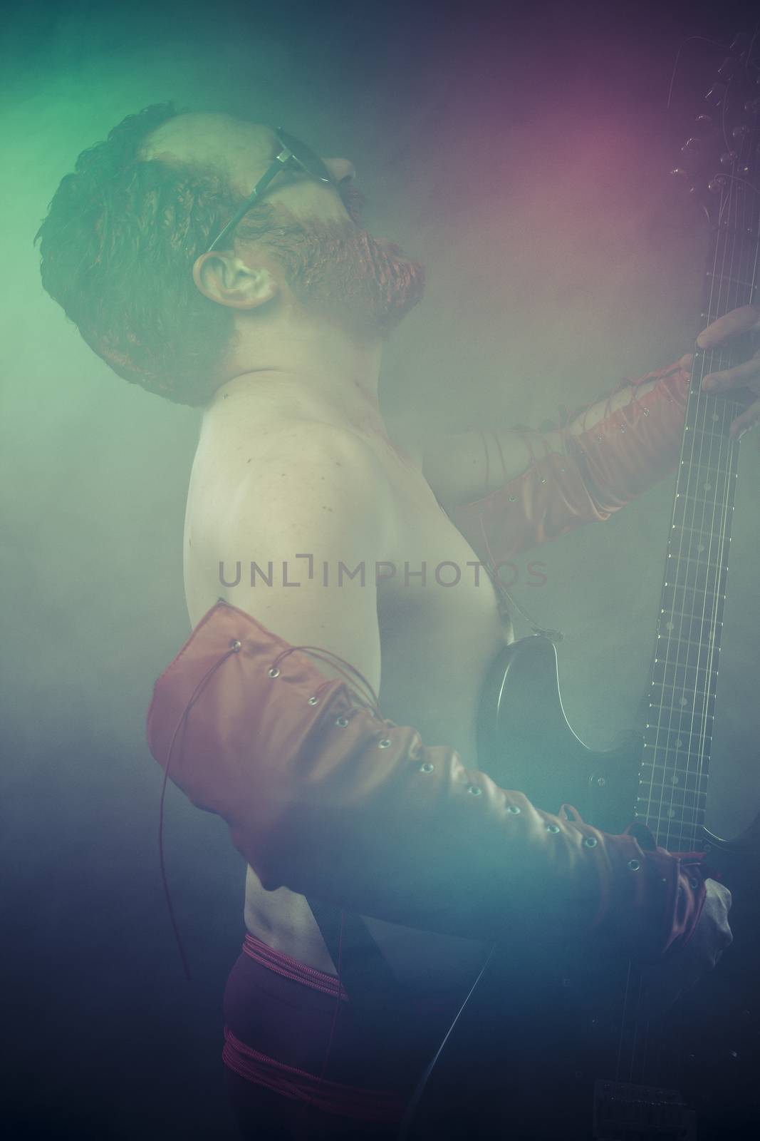 Punk, rocker man with electric guitar in a rock concert by FernandoCortes