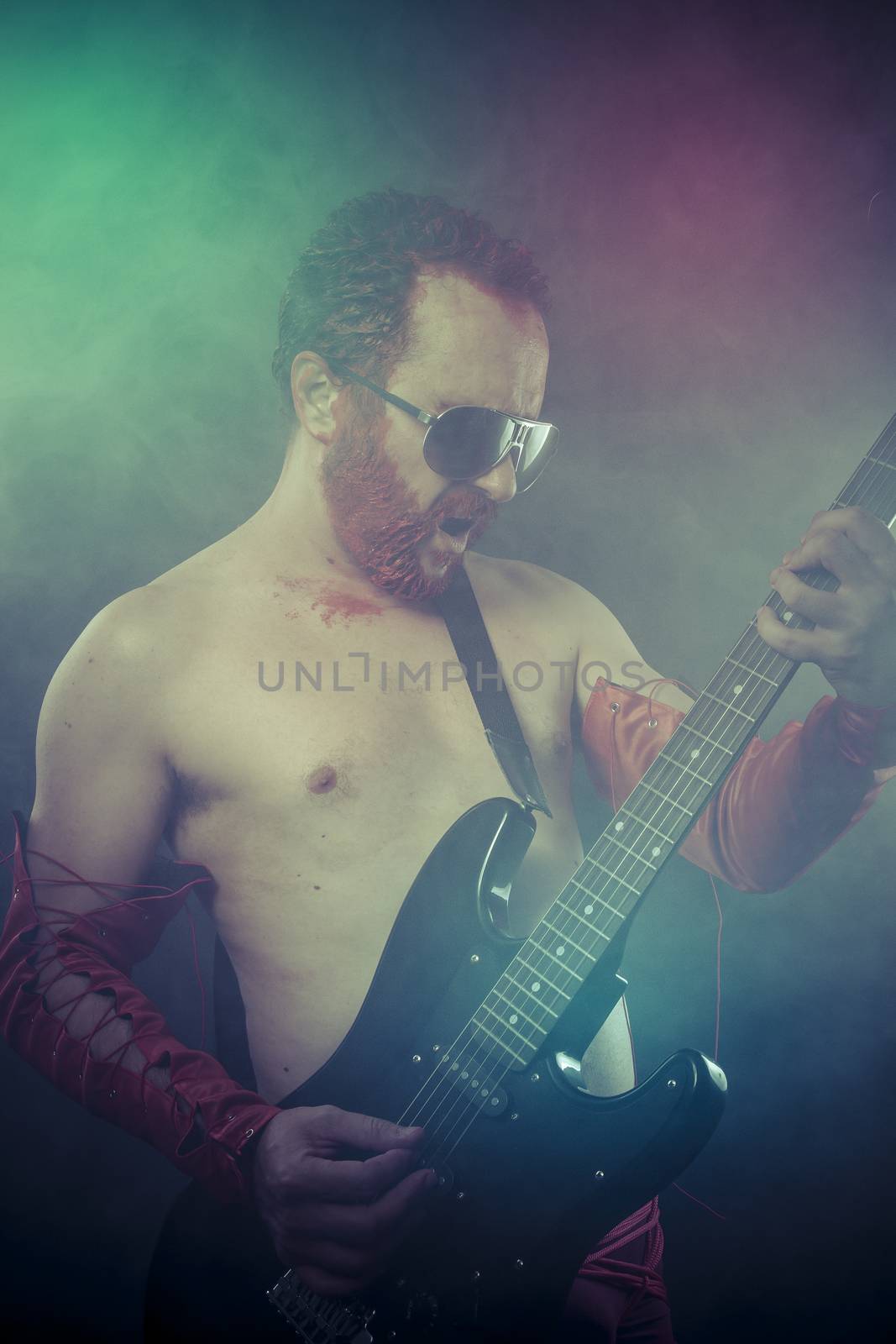 Heavy, rocker man with electric guitar in a rock concert by FernandoCortes
