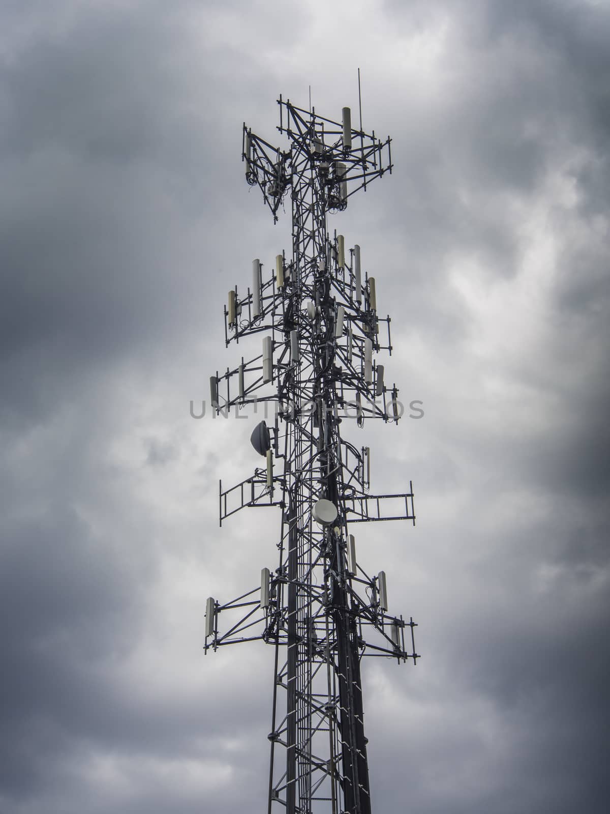 Mobile phone antenna tower against a dark stormy sky