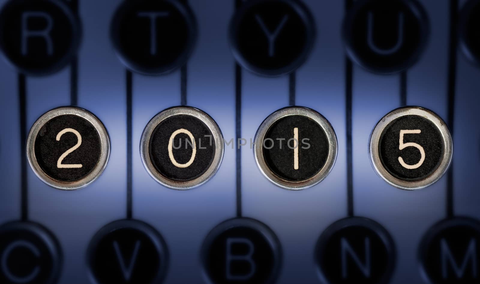 Image of old typewriter keyboard with scratched chrome keys that form "2015". Lighting and focus are centered on "2015". 