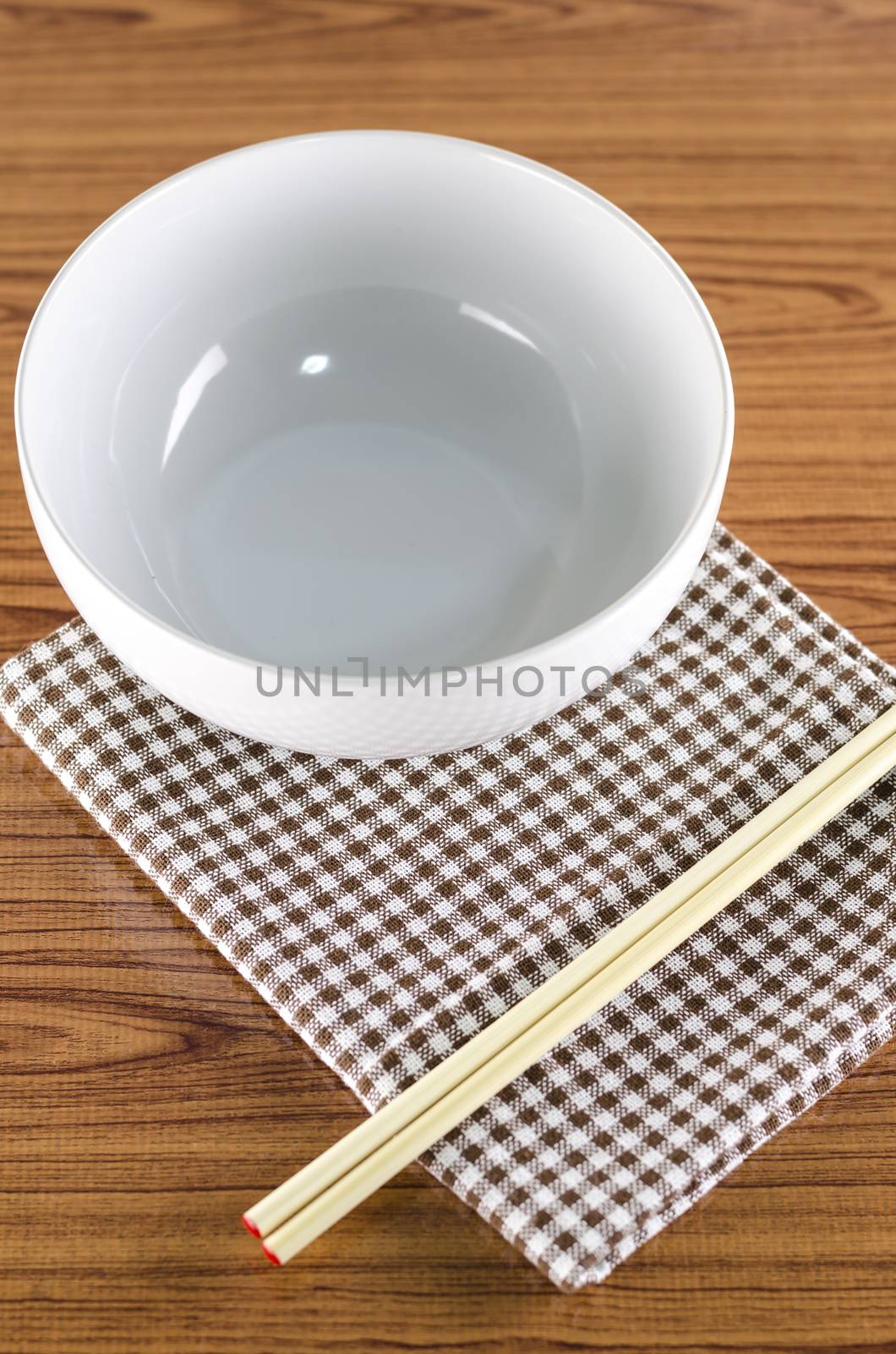 white bowl and chopstick with kitchen towel on wood background