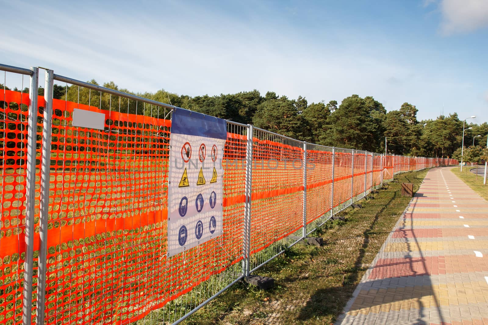 A orange fence with warning signs on it