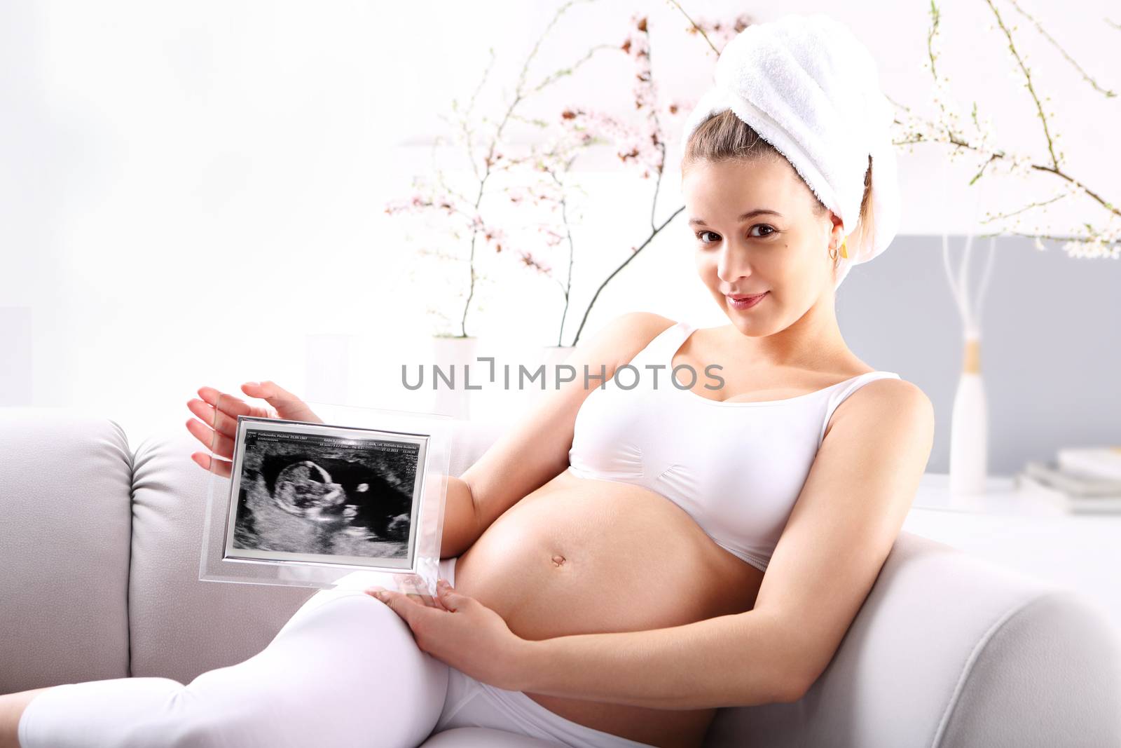 Young expectant mother ultrasound shows the baby sitting on the sofa