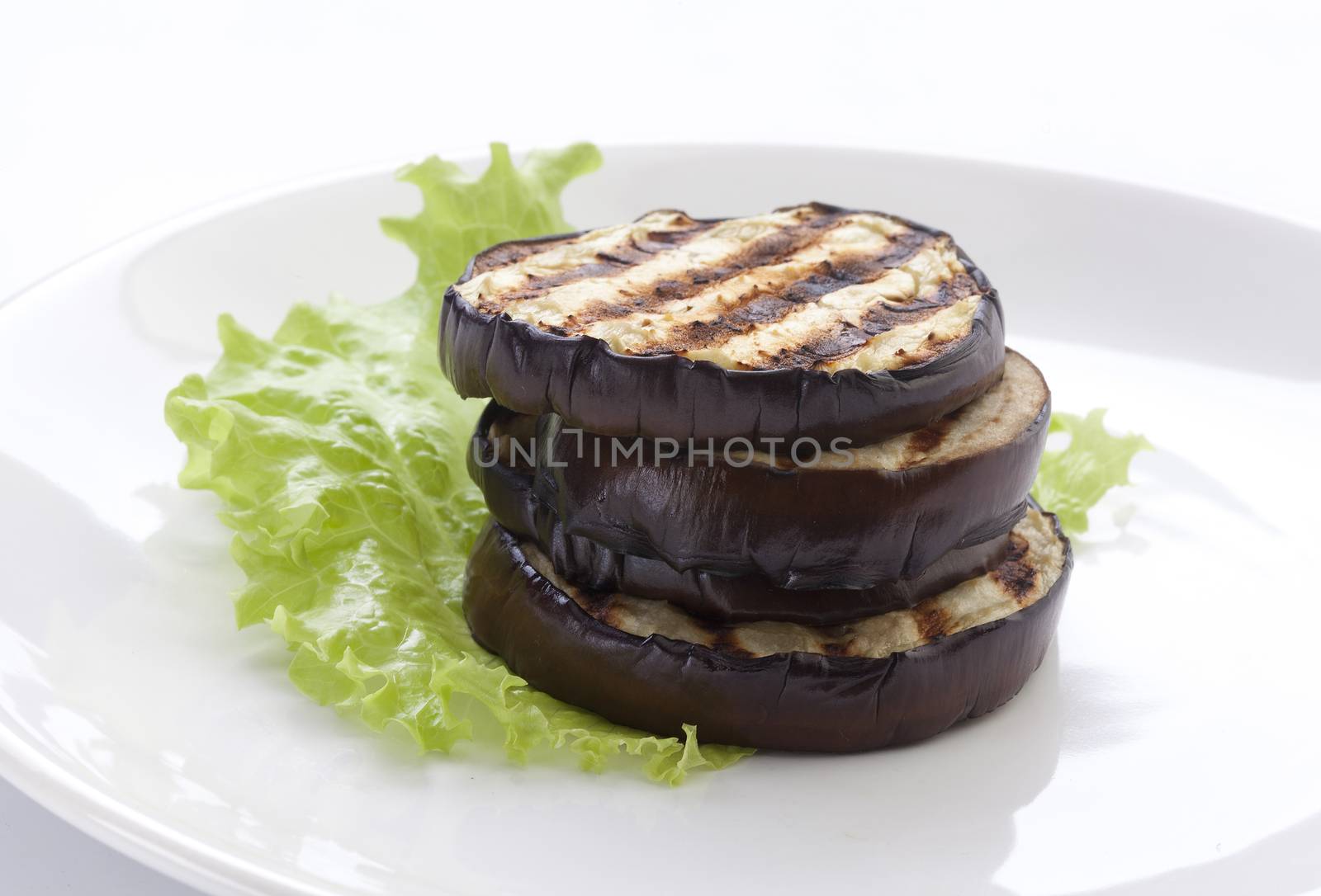 Some fried slices of eggplant with fresh green lettuce on the plate