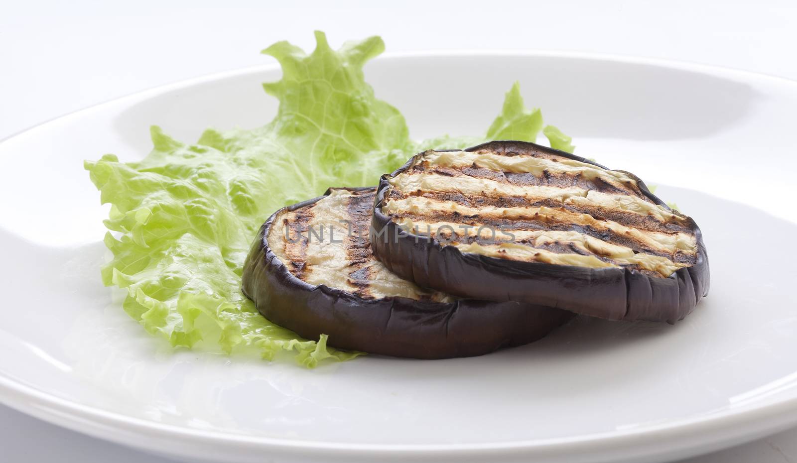 Some fried slices of eggplant with fresh green lettuce on the plate