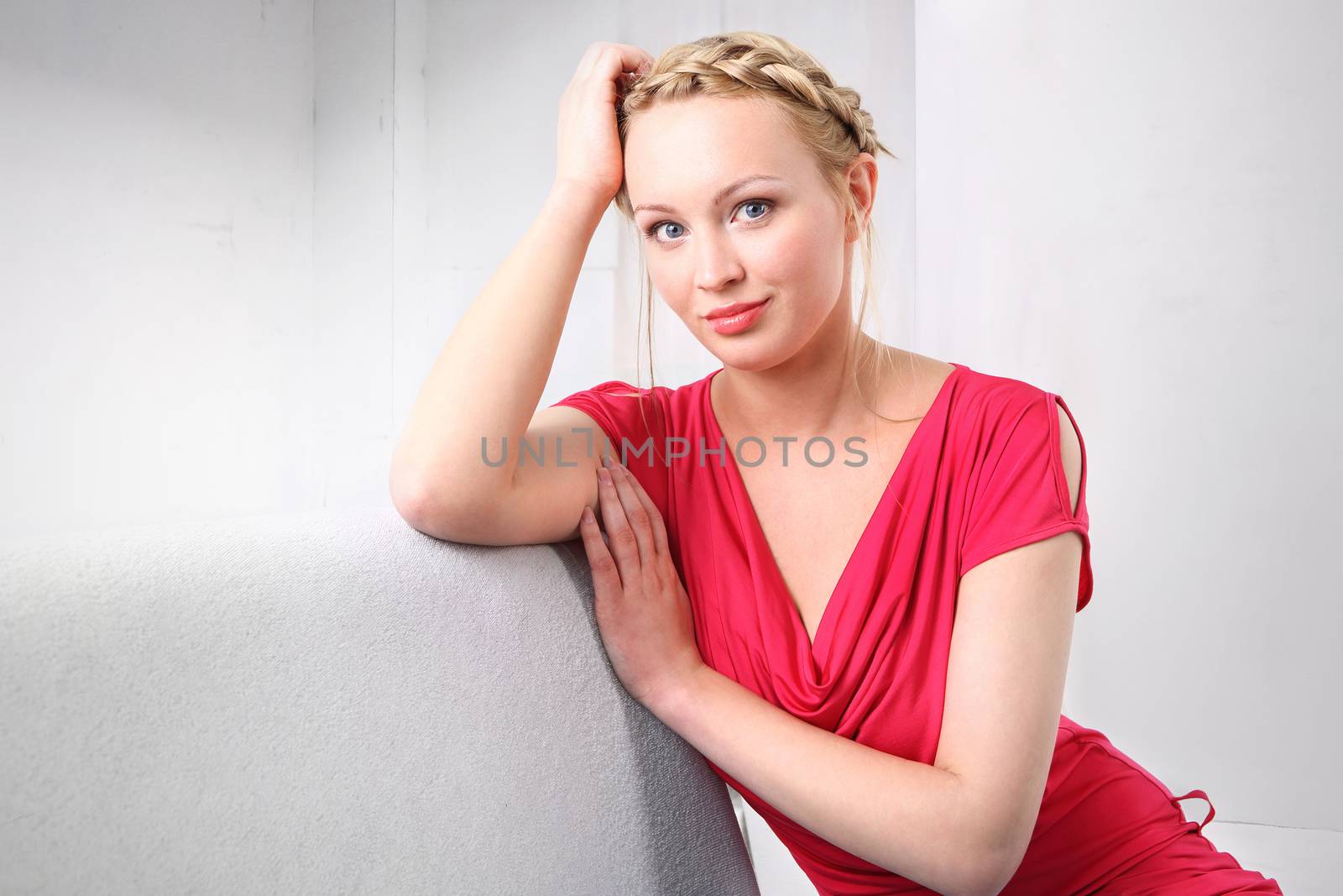 Attractive woman sitting on a gray sofa and meditates.