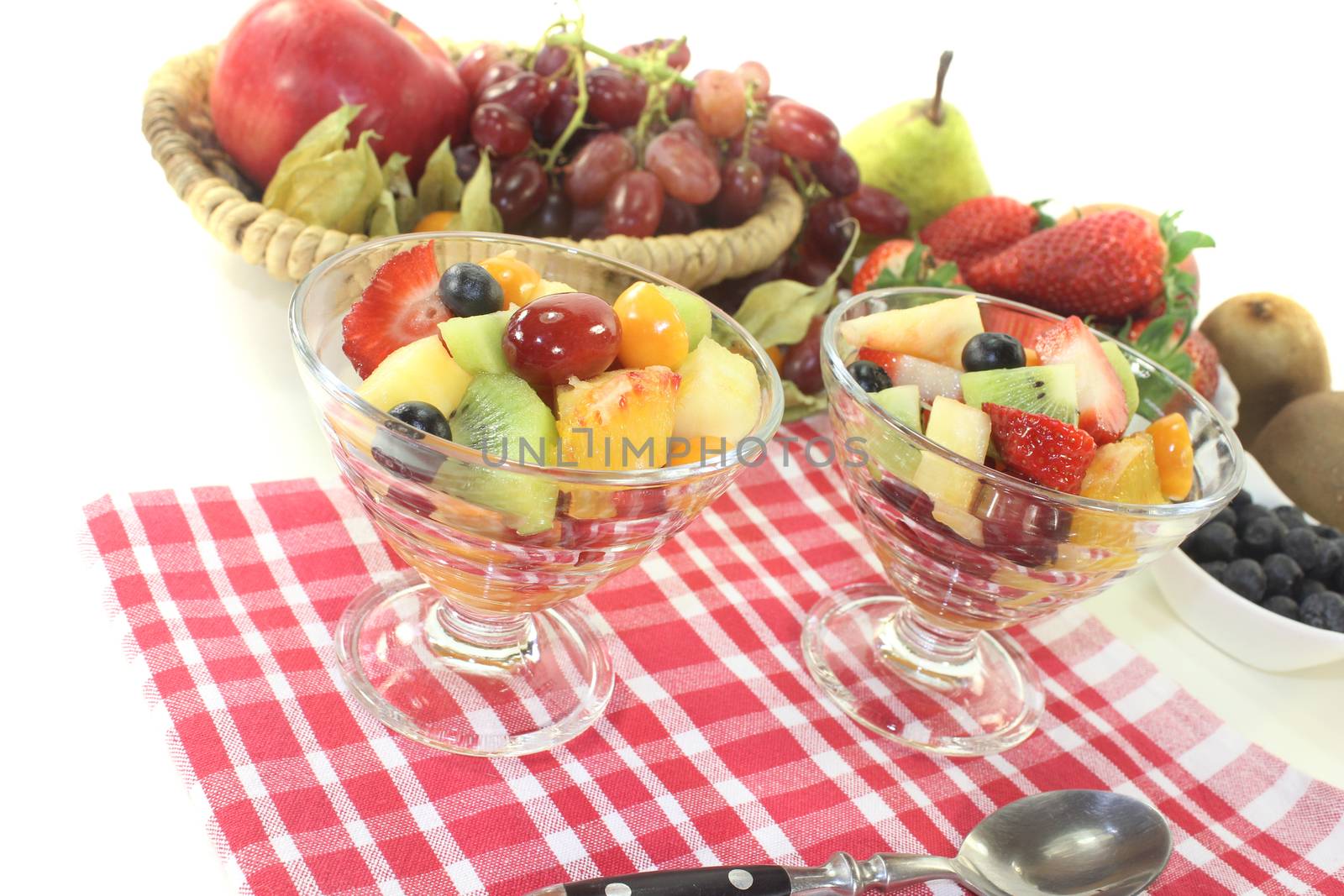 Fruit salad in a bowl on checkered napkin before light background