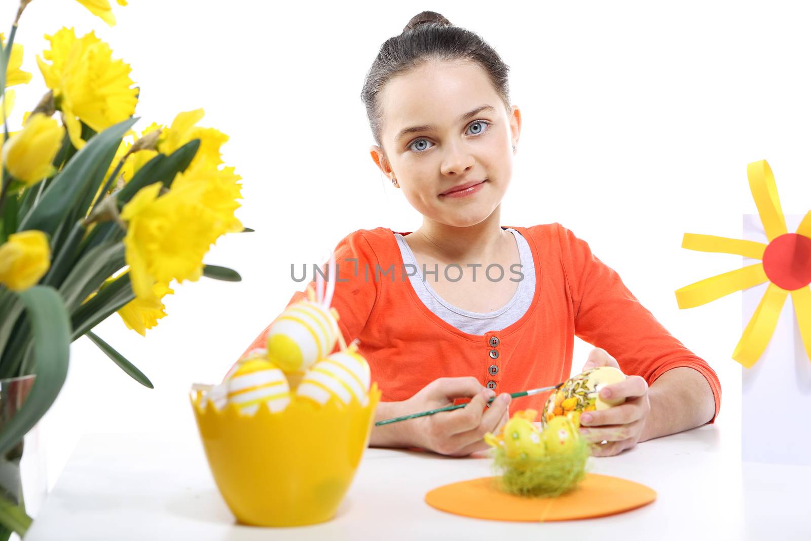 Cheerful little girl painting Easter eggs