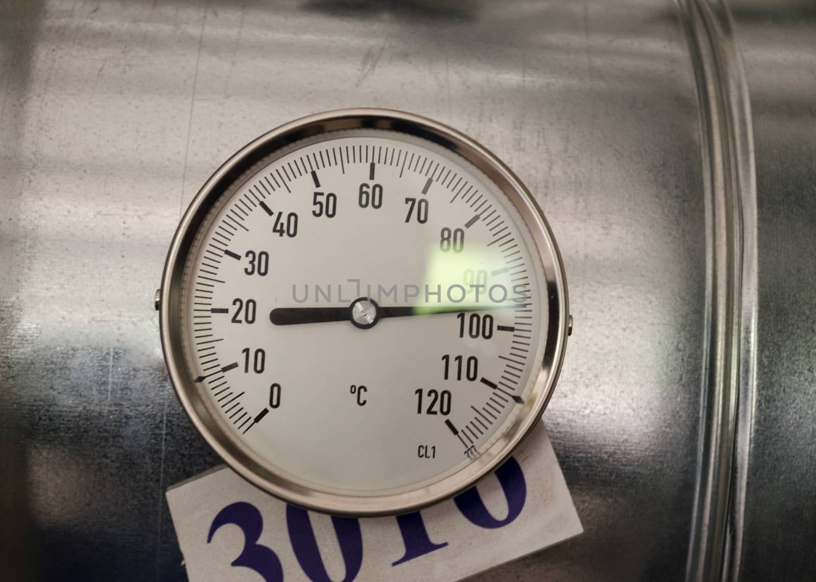 Circular industrial thermometer temperature meter show almost hundred degree celsius.