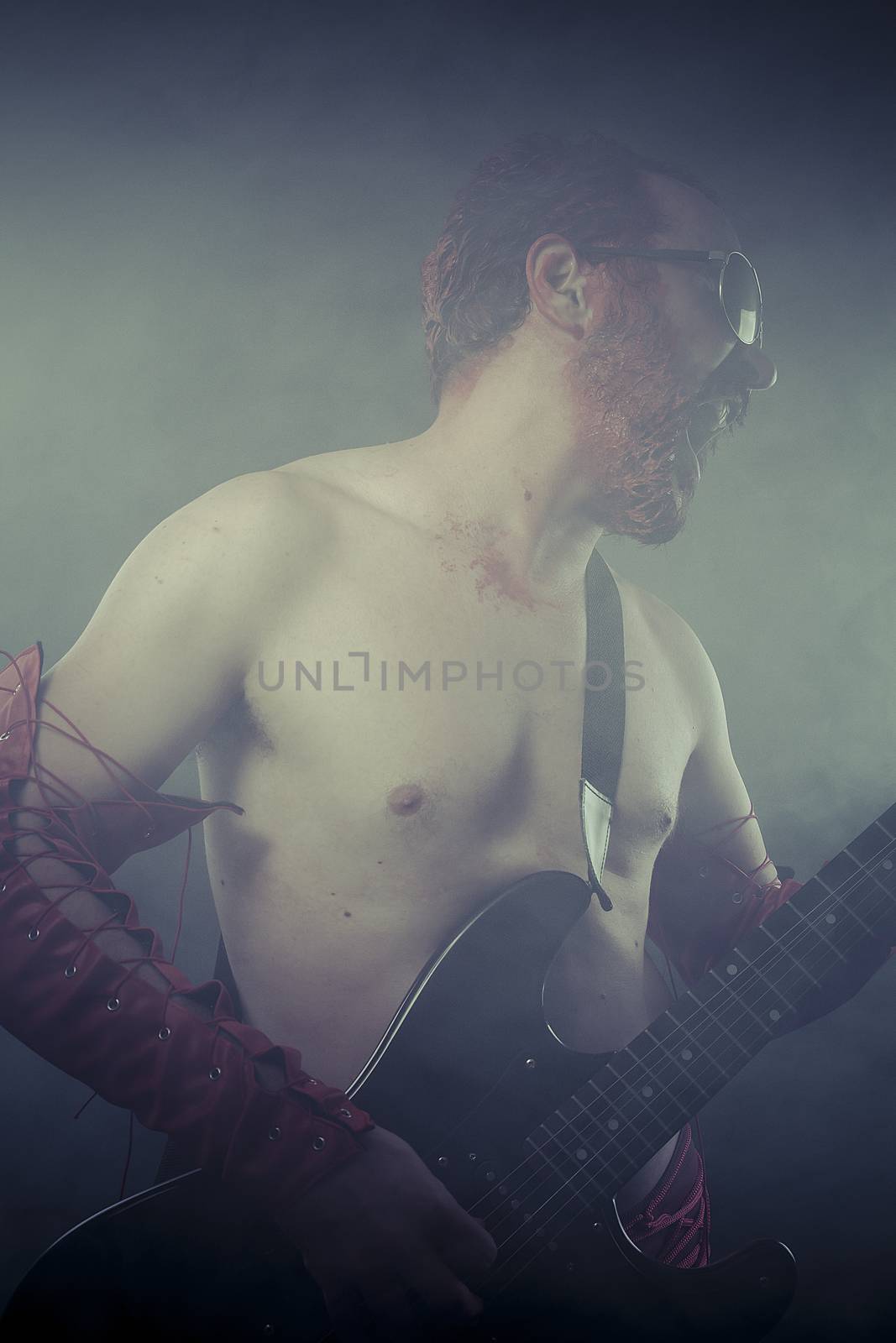 Heavy, rocker man with electric guitar in a rock concert by FernandoCortes