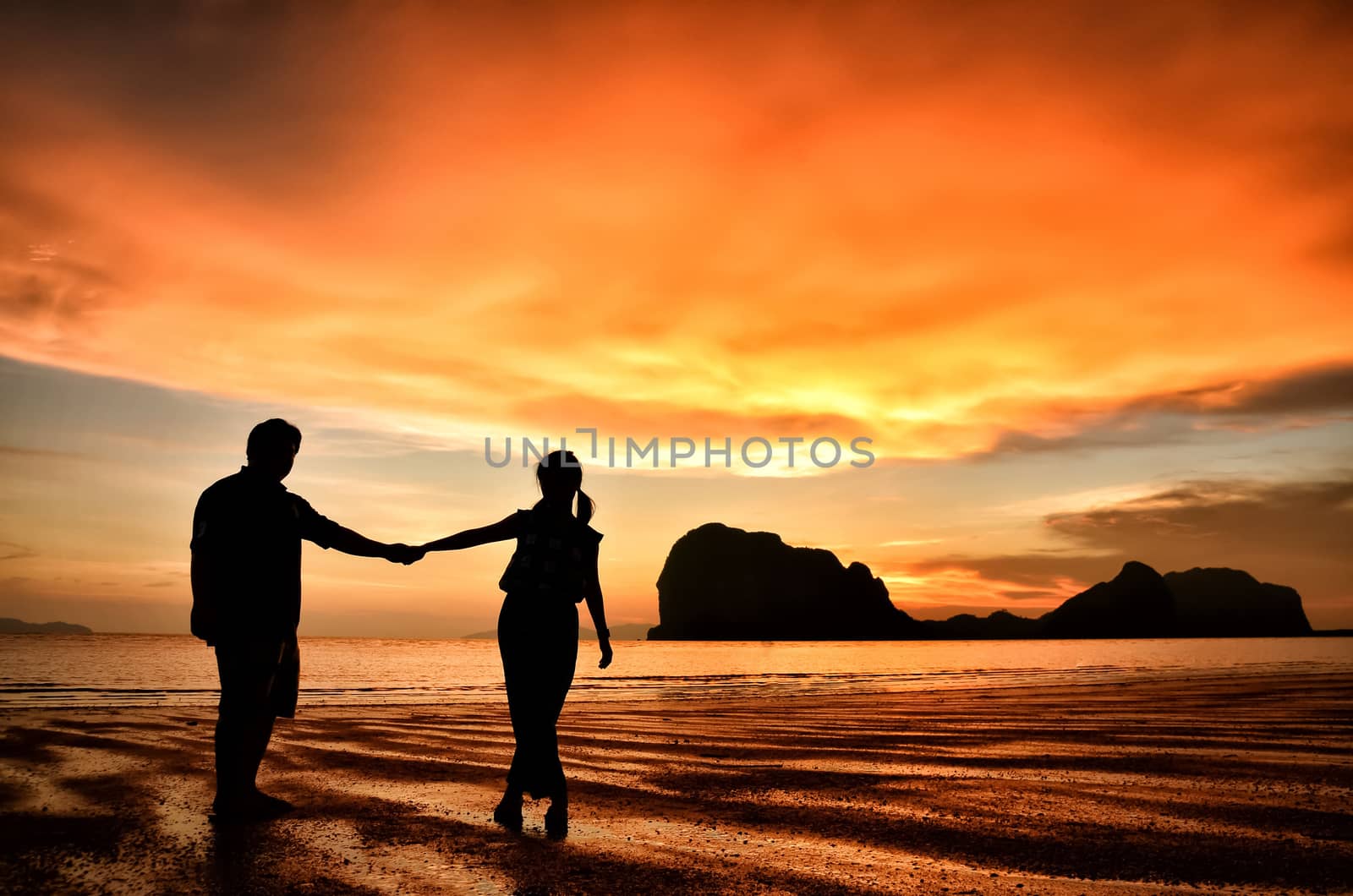 Romantic couple holding hands at sunset on the beach
