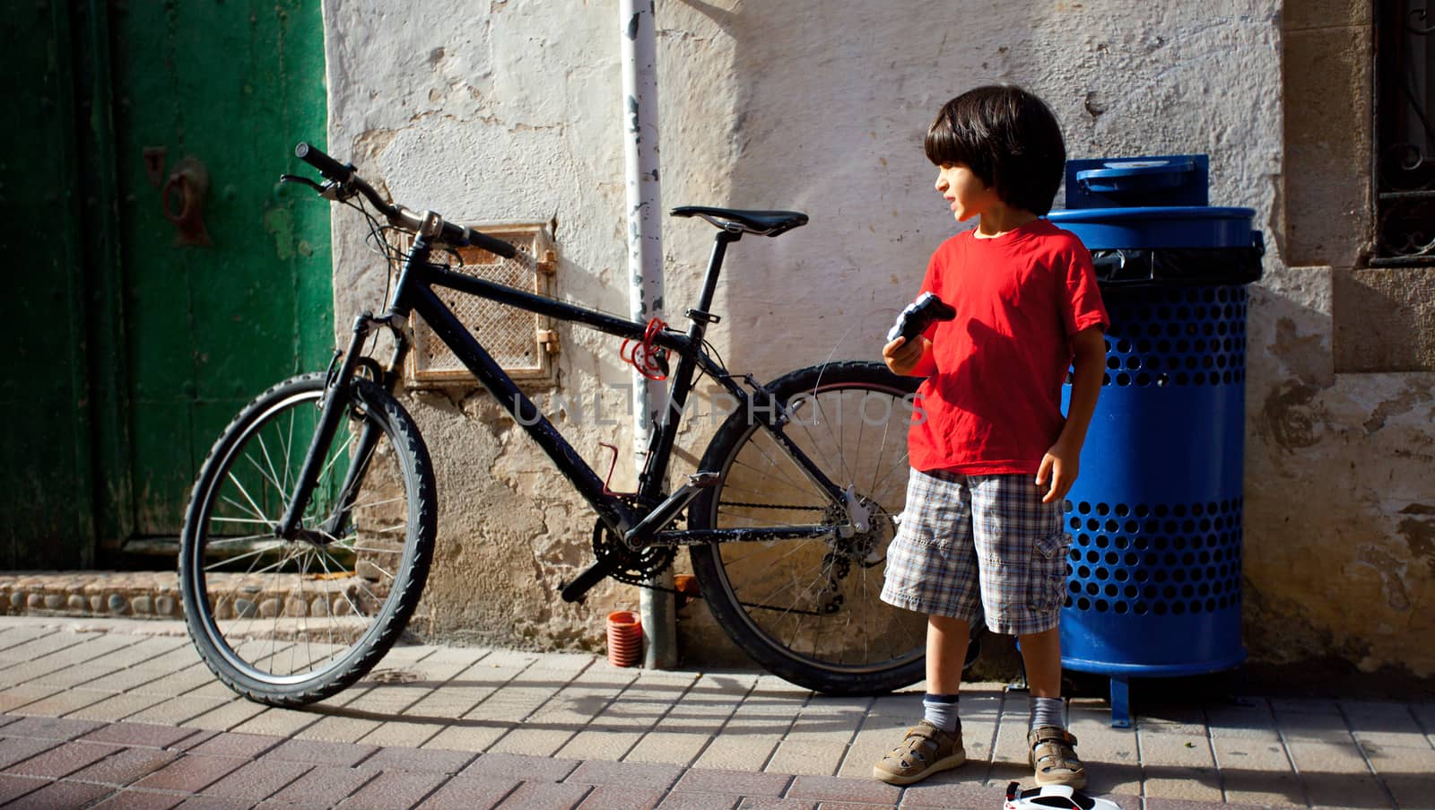 boy in a red T-shirt near the vintage bicycle on an old spanish street in Tossa de Mar