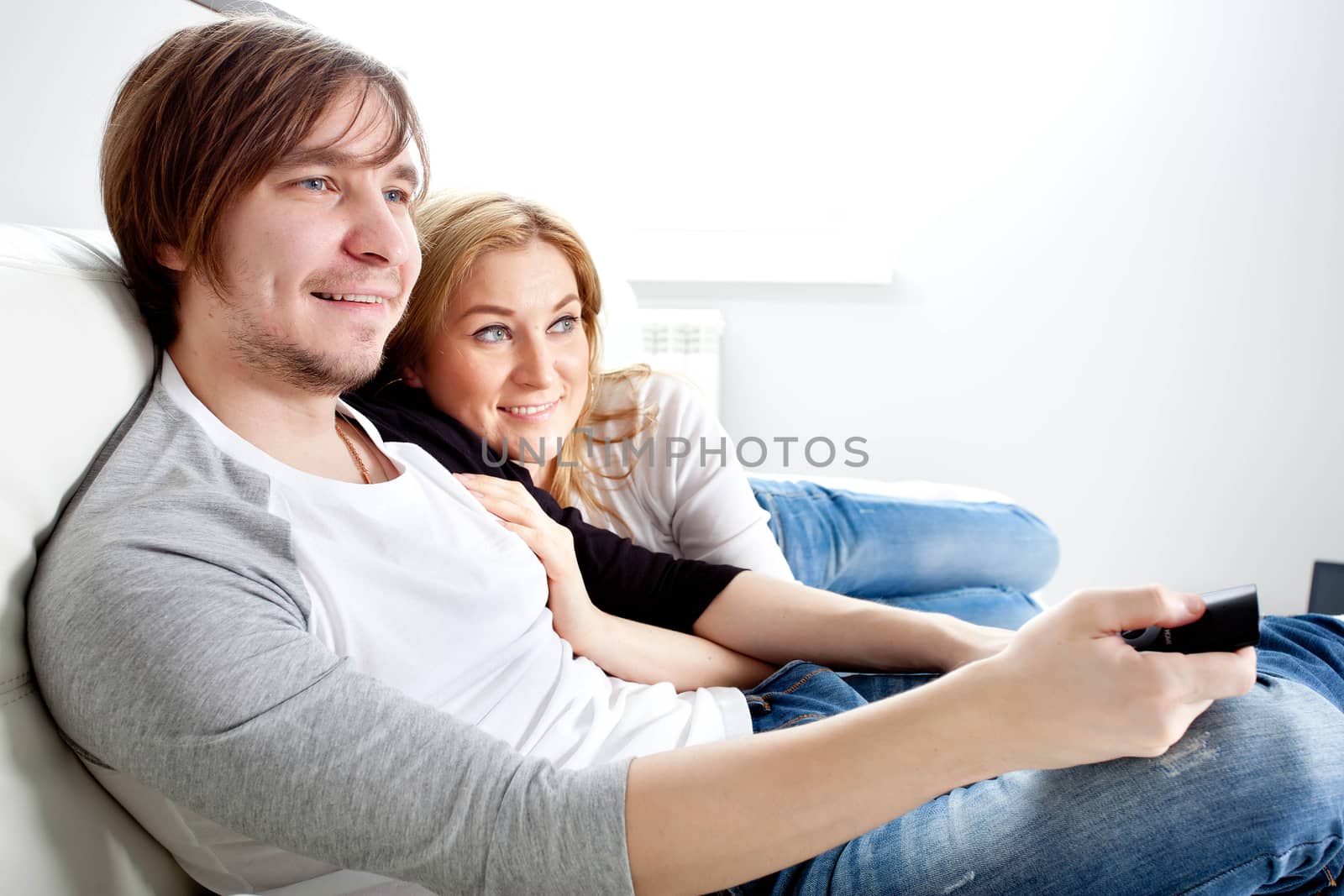 Happy couple watching TV in living room 
