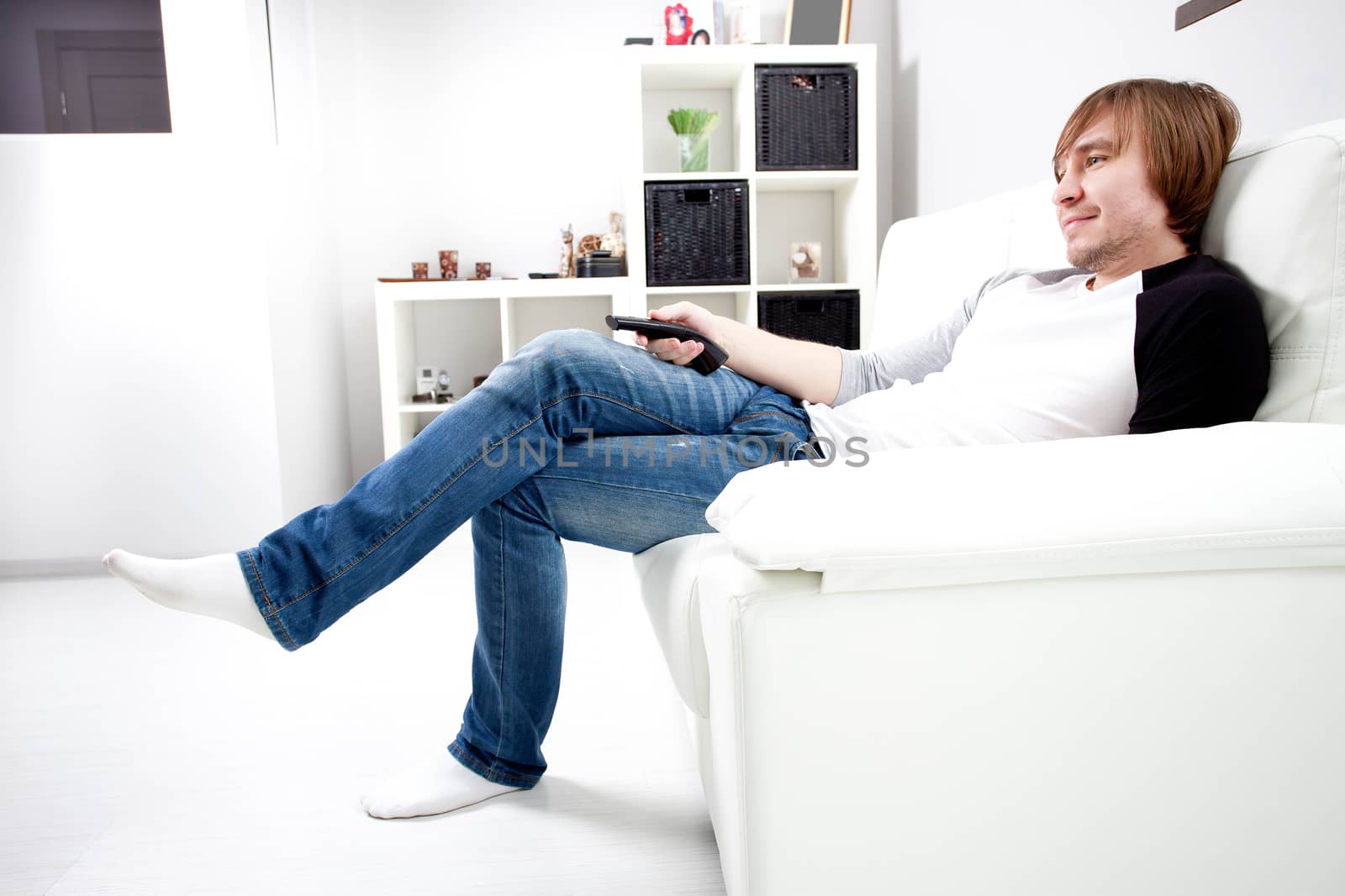 smiling happy man on cosy sofa  with remote control tv