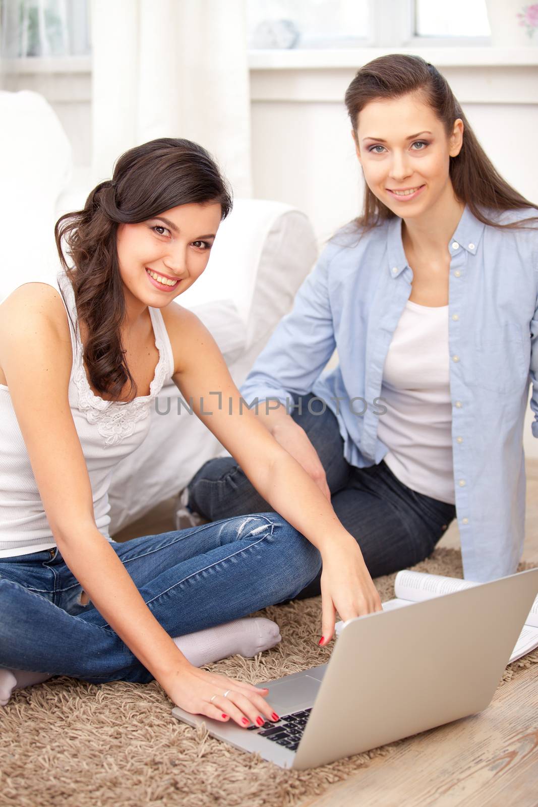 two young  women resting with notebook on floor near sofa, at campus