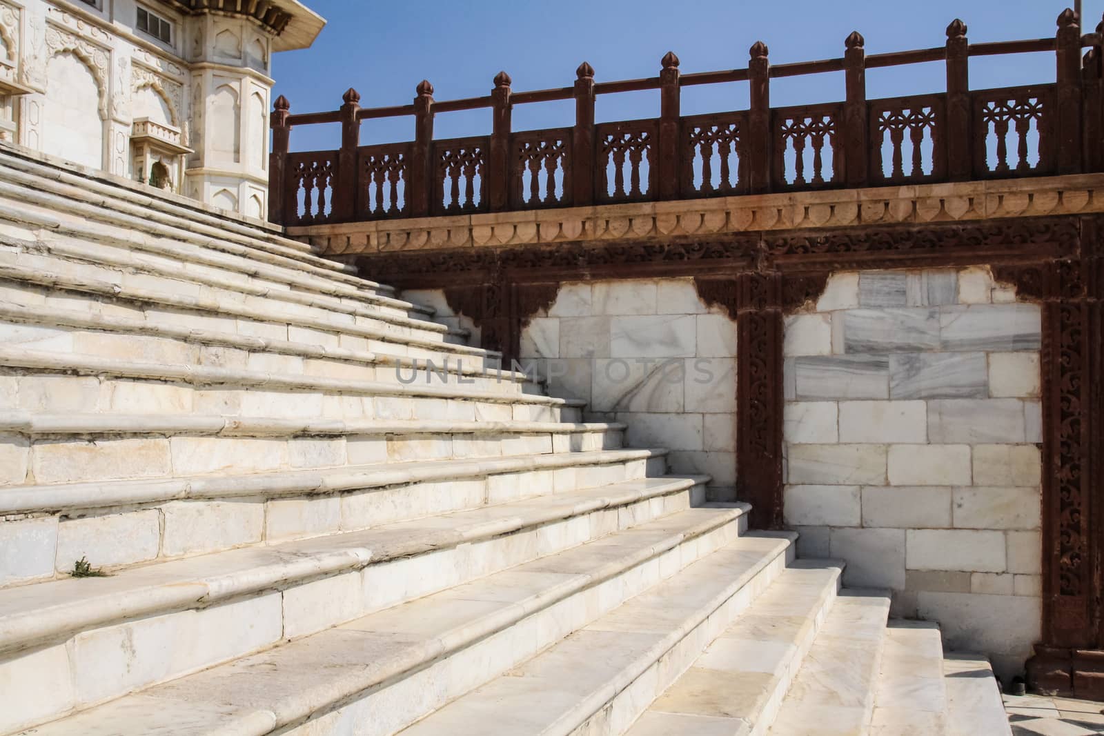 Jaswant Thada in Jodhpur Rajasthan India .White Marble Construction with contrasting use of red sandstone for pillars and balustrade carvings. marble stairway with red stone balustrade in morning sunlight against clear blue sky with main centopah partially visible.