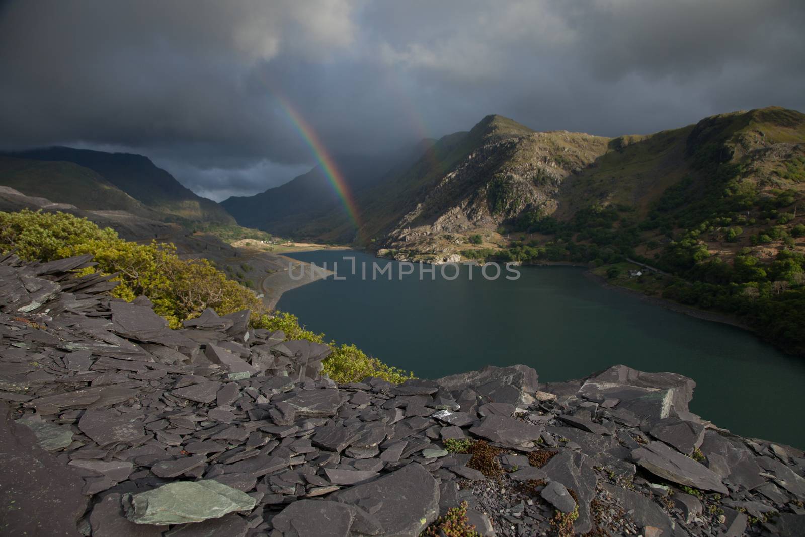 A view across Llyn Peris to Nant Peris and the Llanberis Pass with a double rainbow. Llanberis, Snowdonia national park, Wales, UK