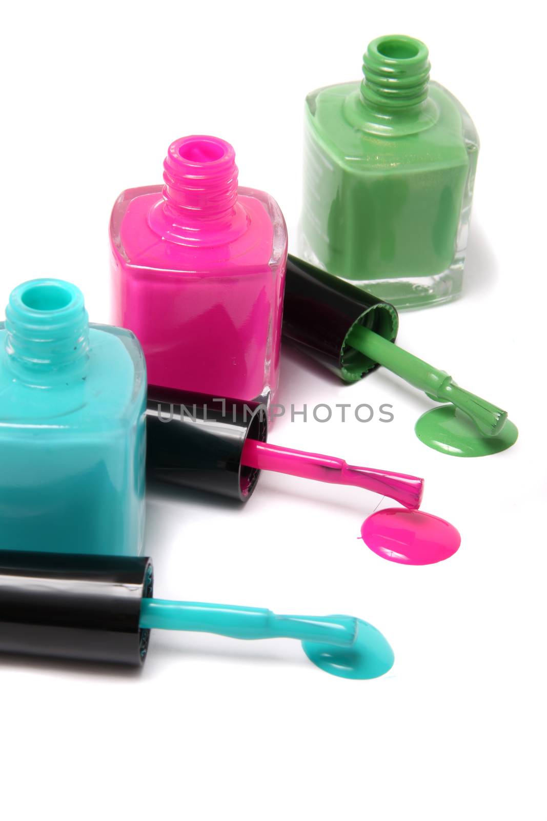 Nail polish bottles and spots in bright spring or summer colors in light blue, pink and green on a white background