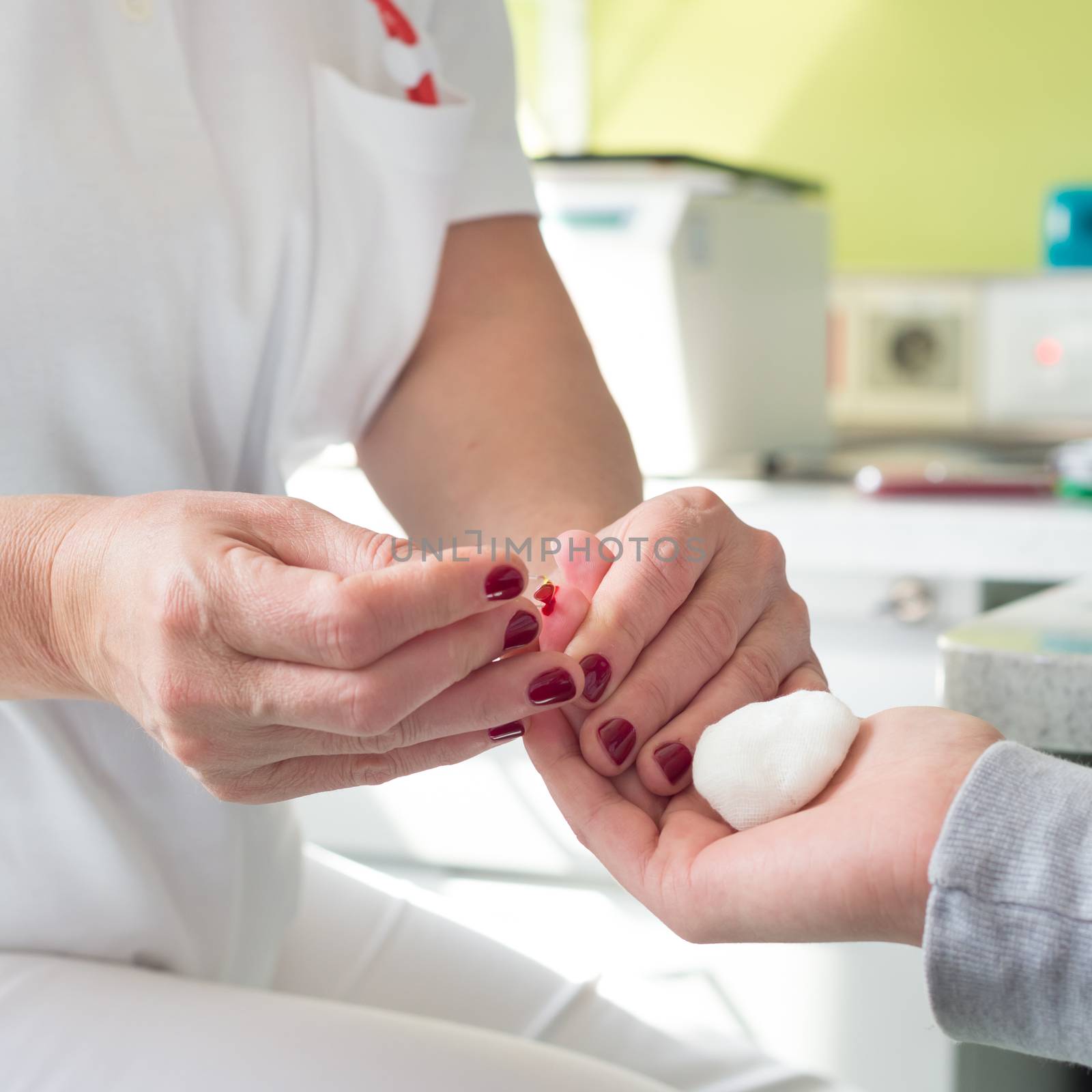 Medical doctor performing a quick prick test for blood group determination by using blood type testing kit with anti A and B antibodies on a white card.