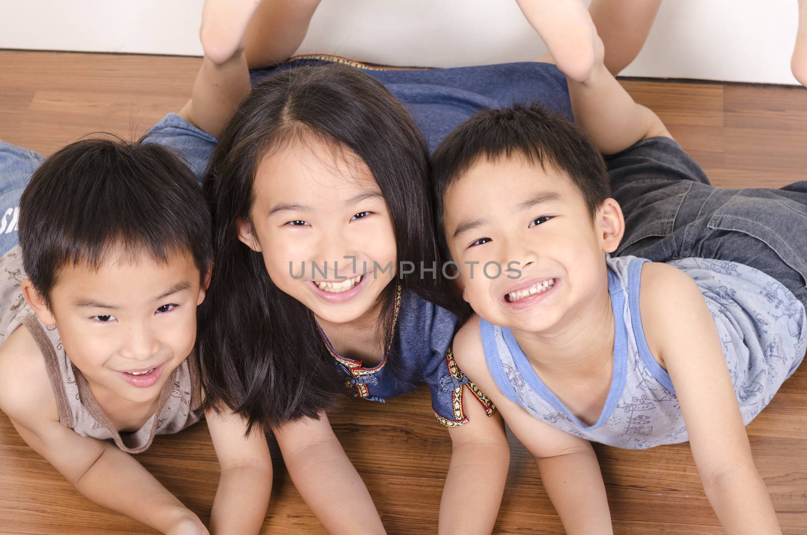 Three happy children lying on floor by FrankyLiu