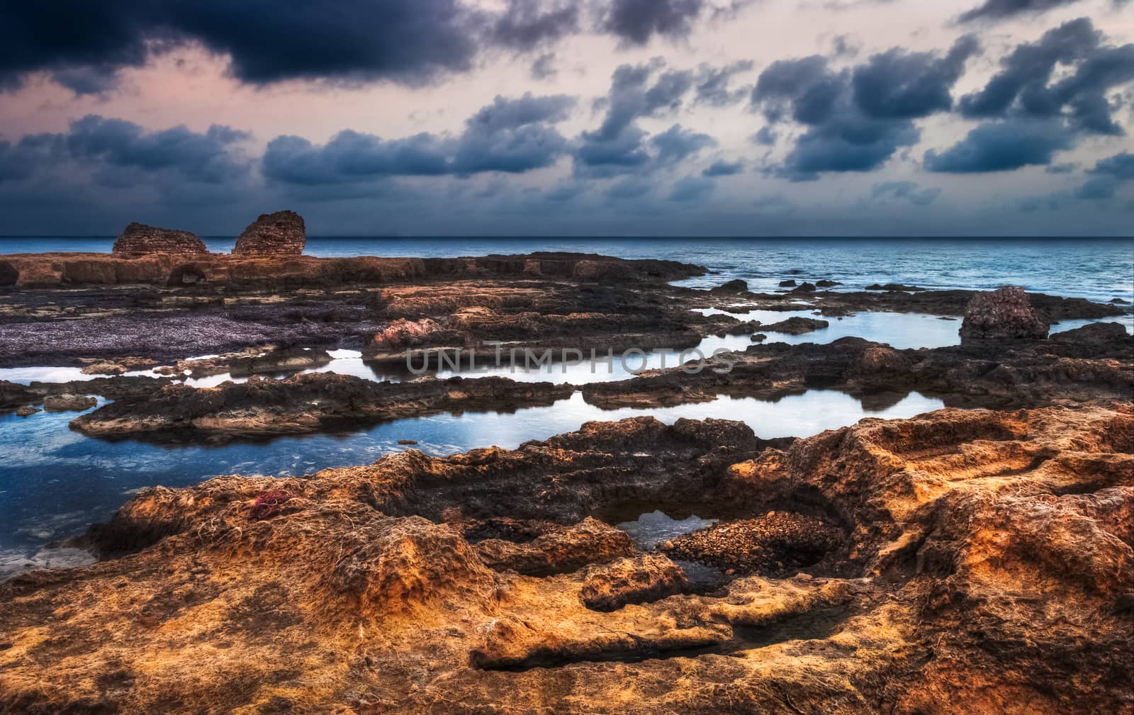 rocky beach with ancient ruins on cloudy morgning