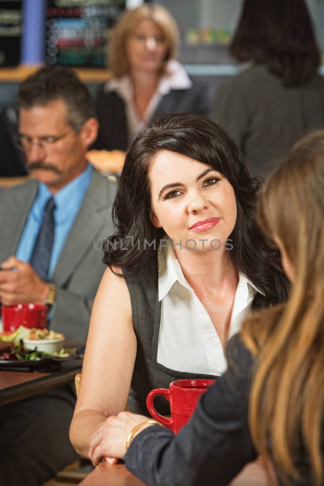 Grinning woman consoled by friend in cafeteria