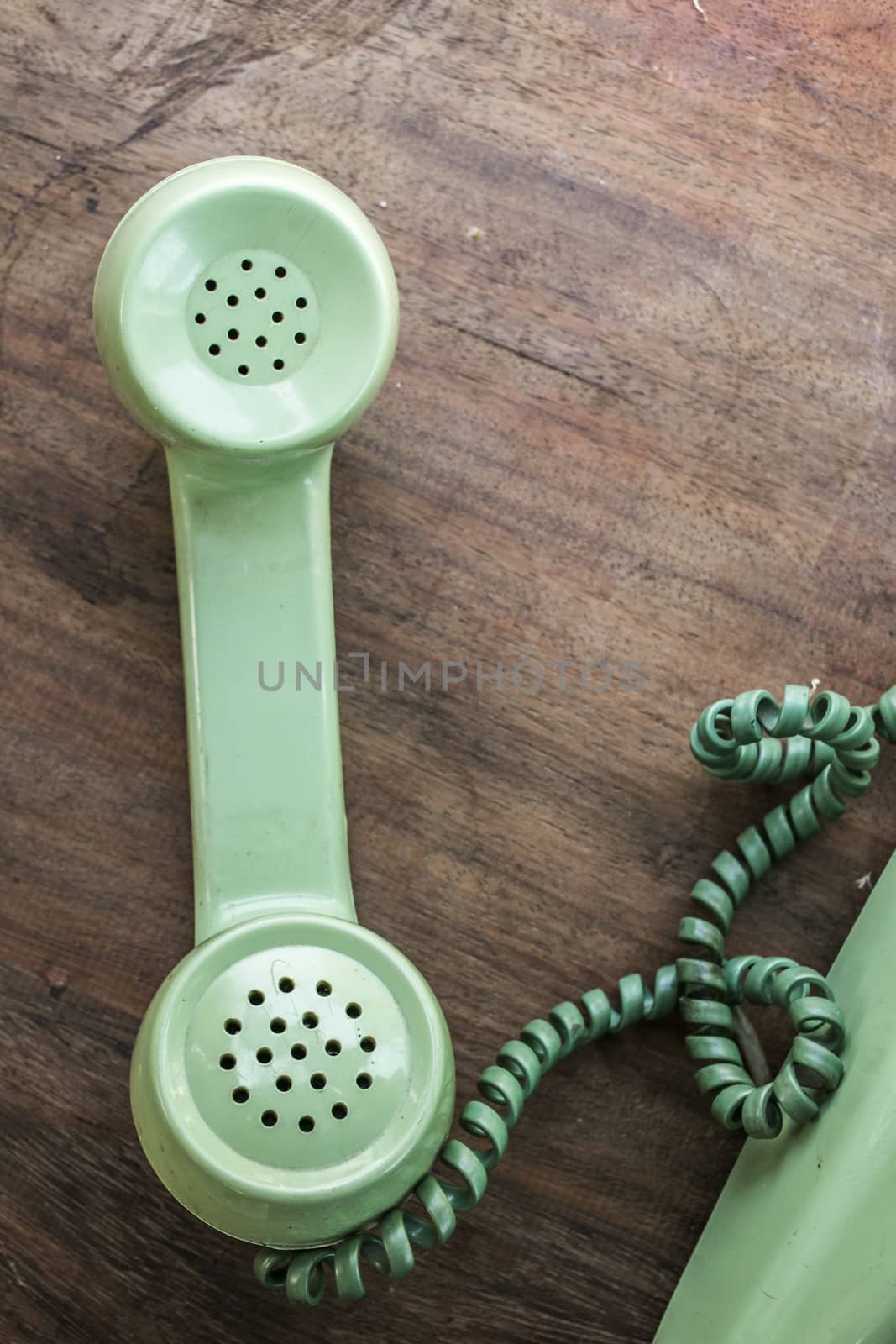 Green vintage telephone on brown wood desk background