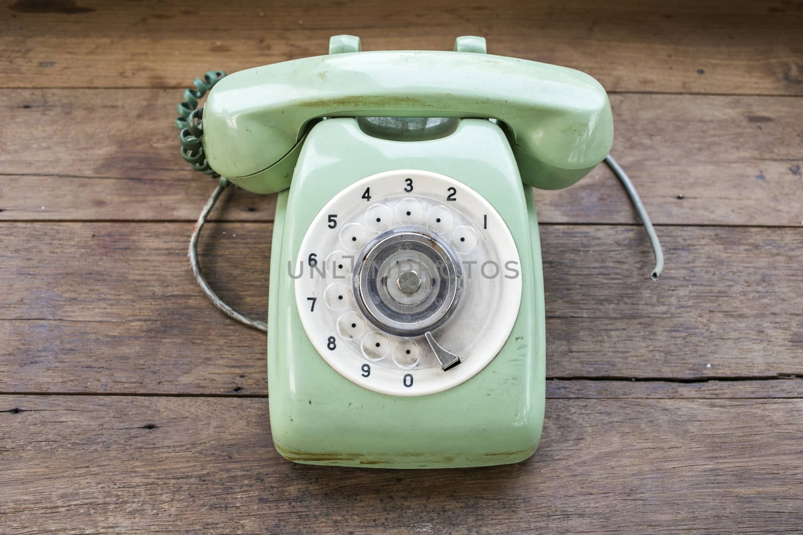 Green vintage telephone on brown wood desk background by 2nix