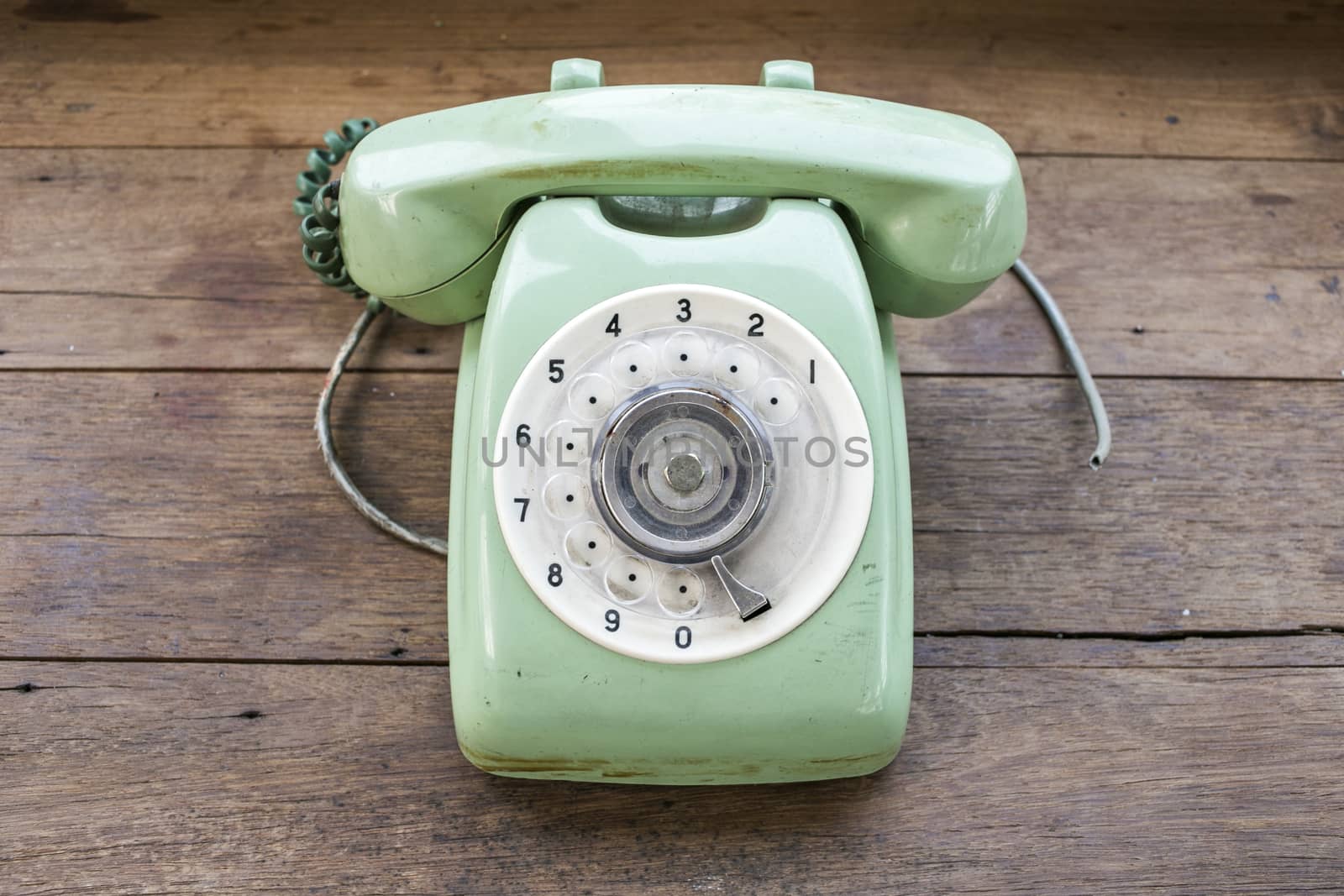 Green vintage telephone on brown wood desk background