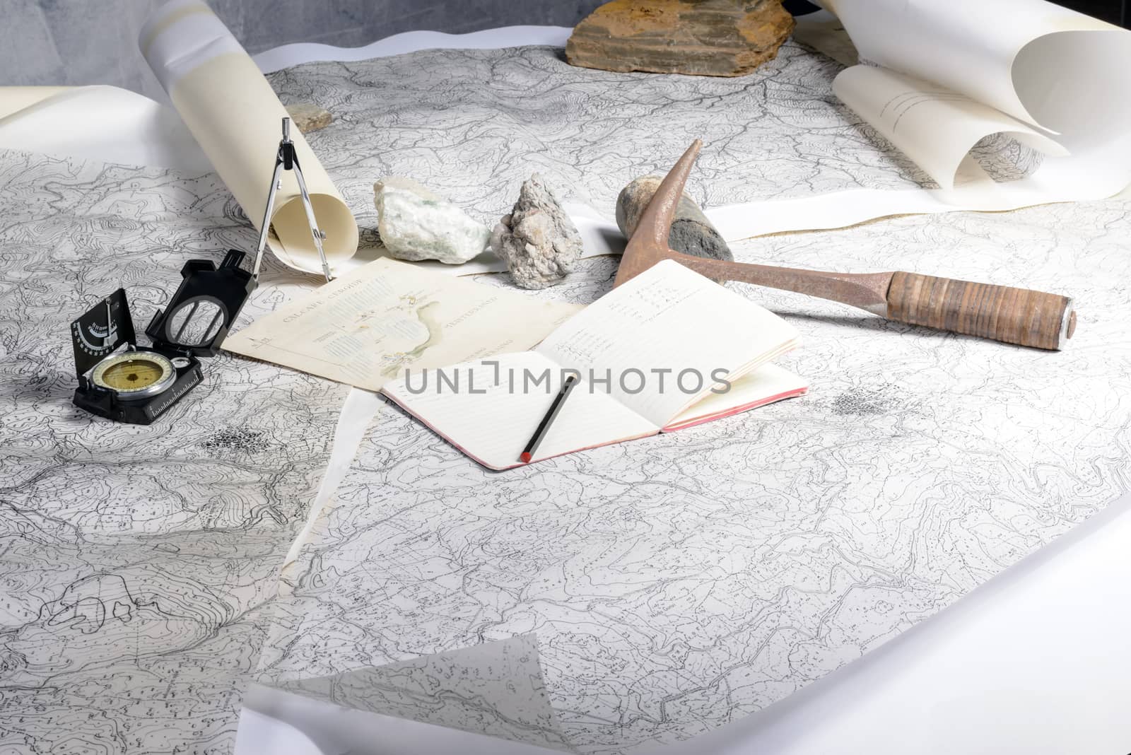 The geological expedition is prepared with the study of topographic maps. On the table the tools of the geologist.