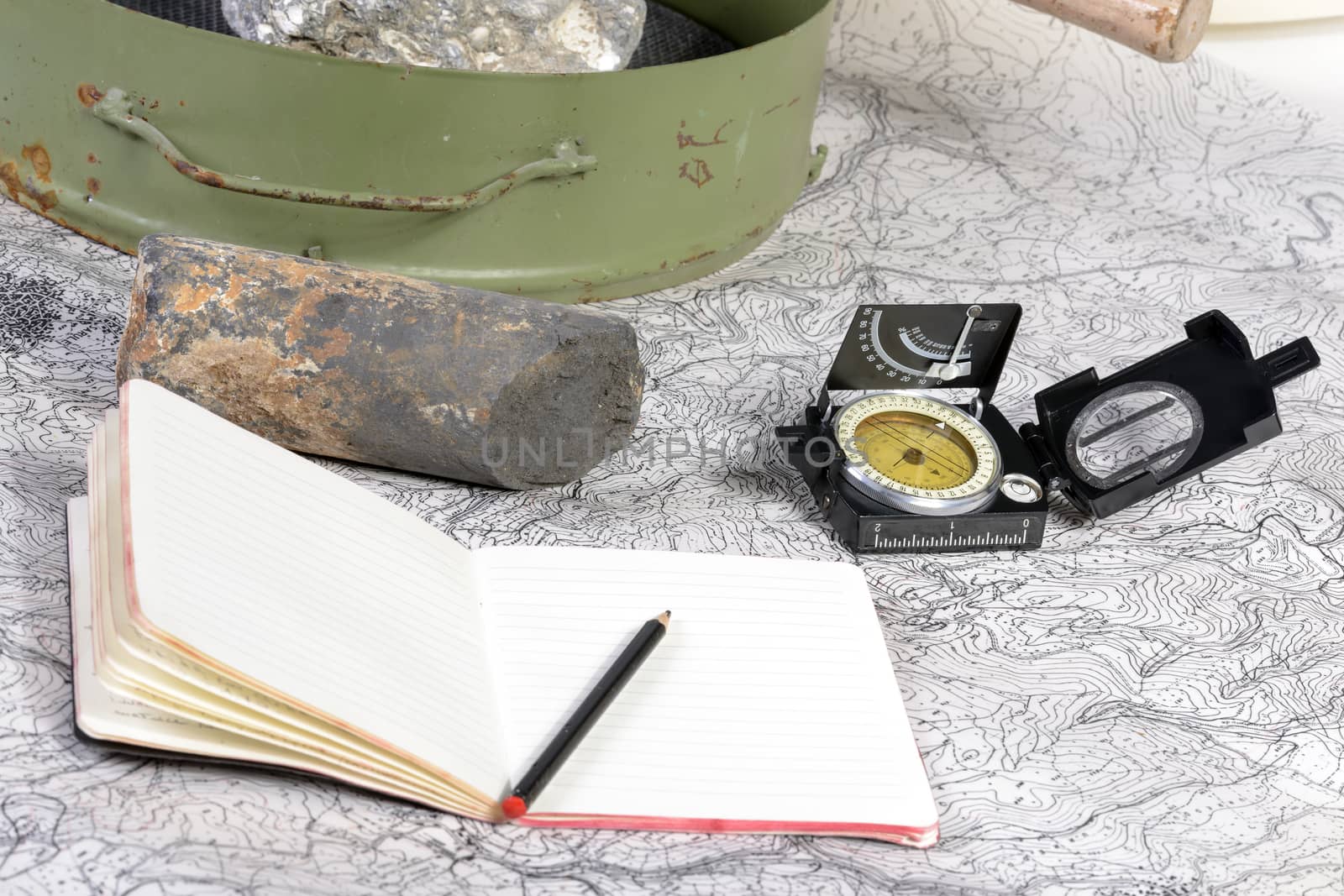 The geological expedition is prepared with the study of topographic maps. On the table the tools of the geologist.